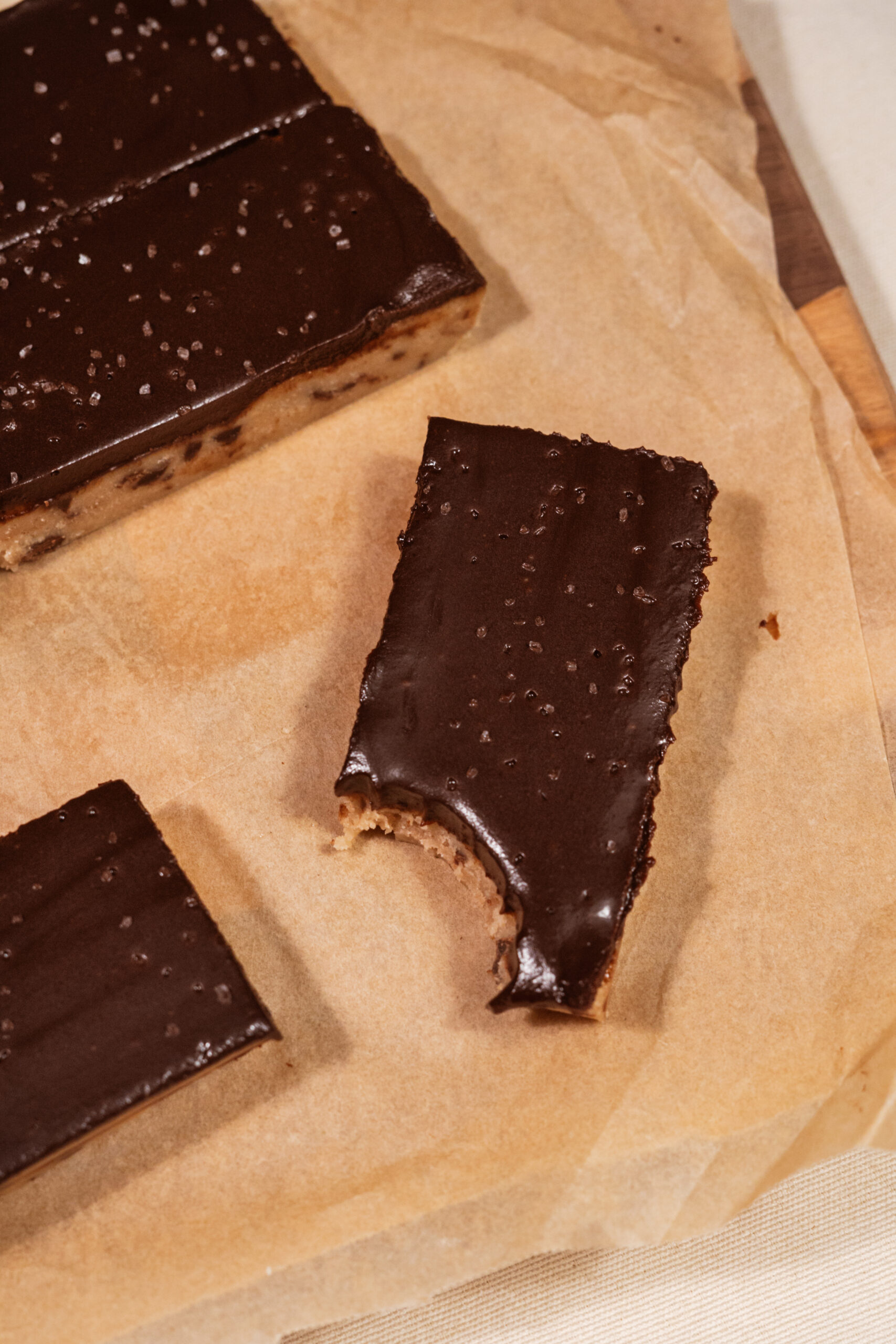 chocolate chip cookie dough bars sliced on parchment paper with bite taken.