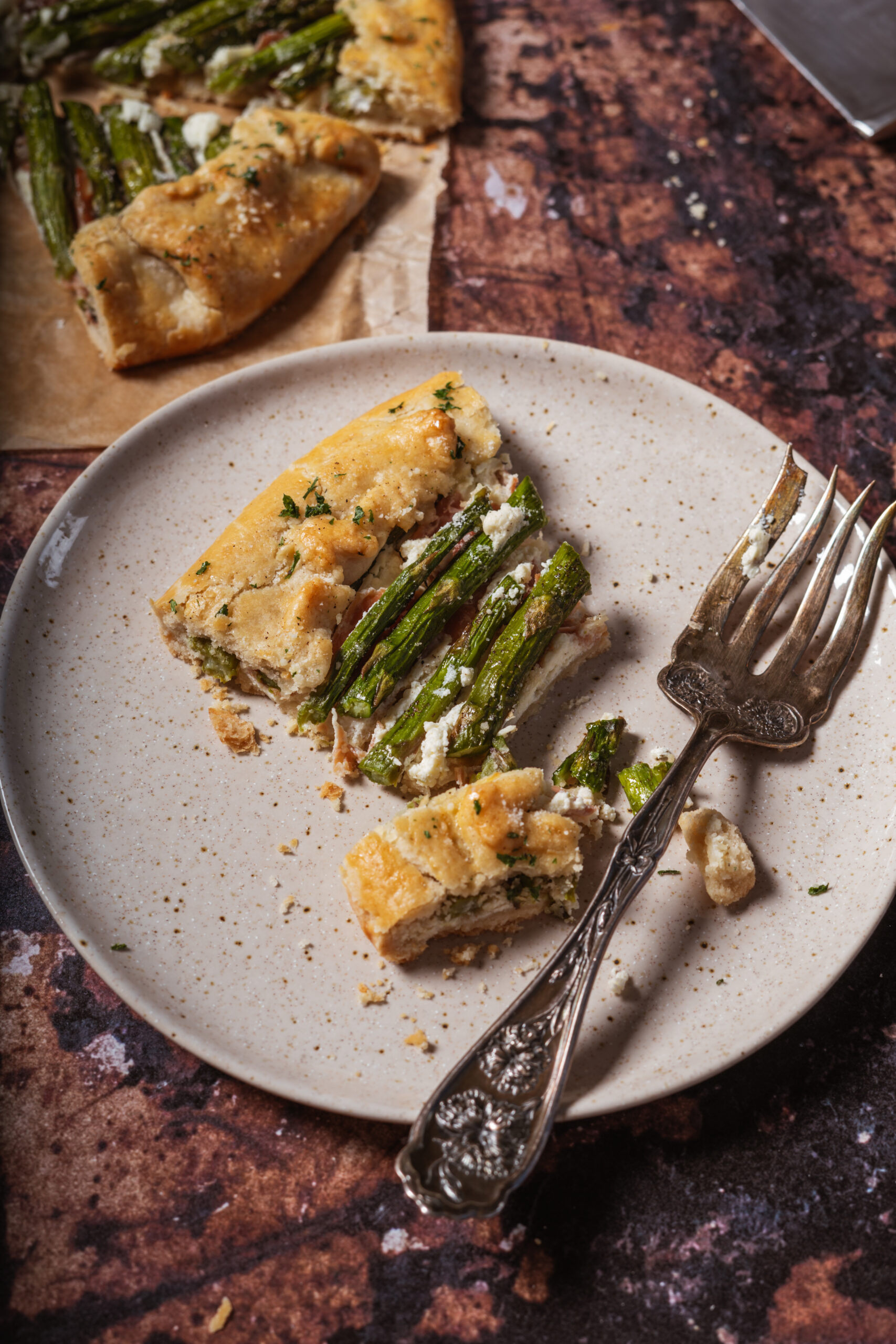 slice of asparagus galette on beige plate with a vintage fork.