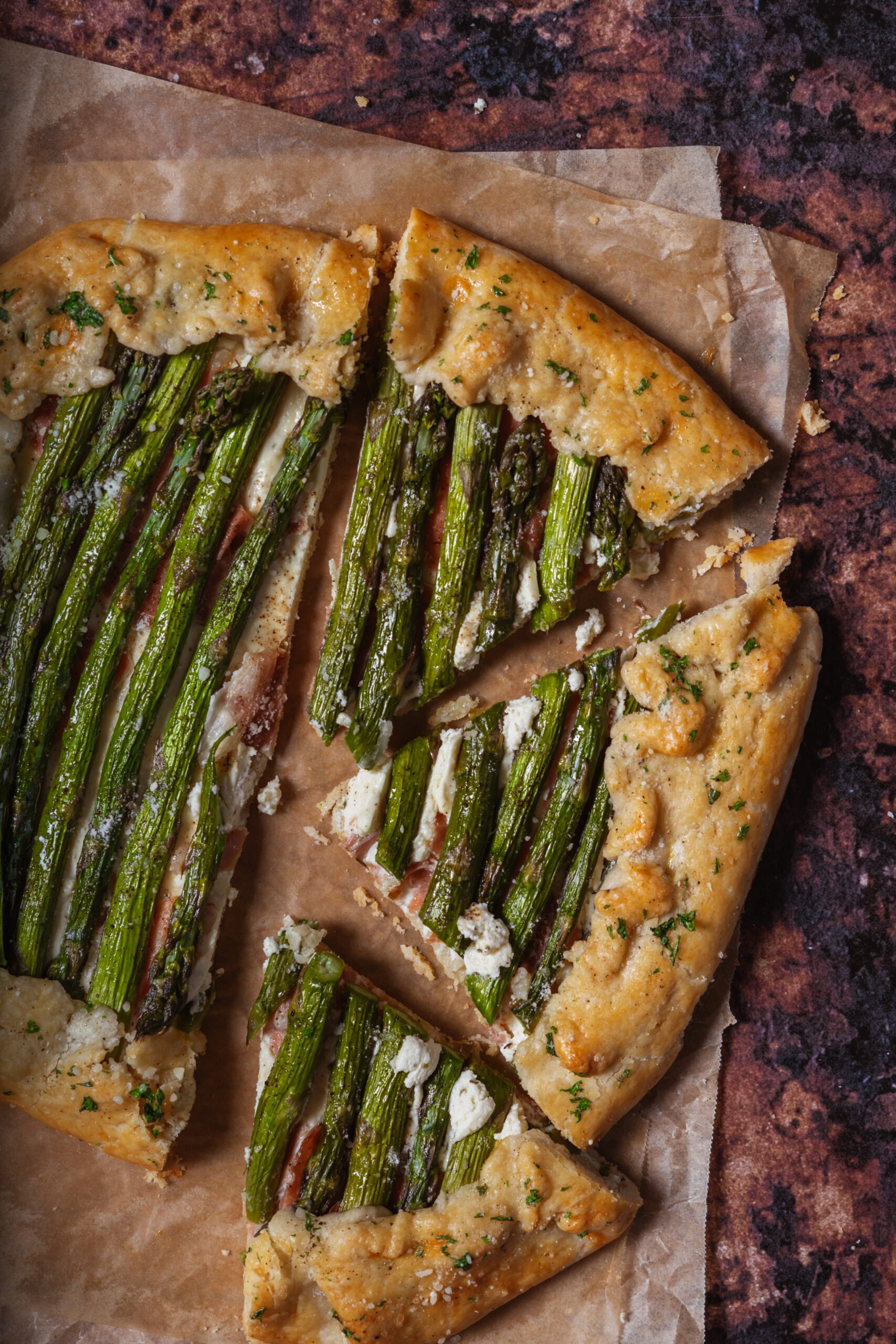 asparagus galette on parchment paper with three slices taken out.