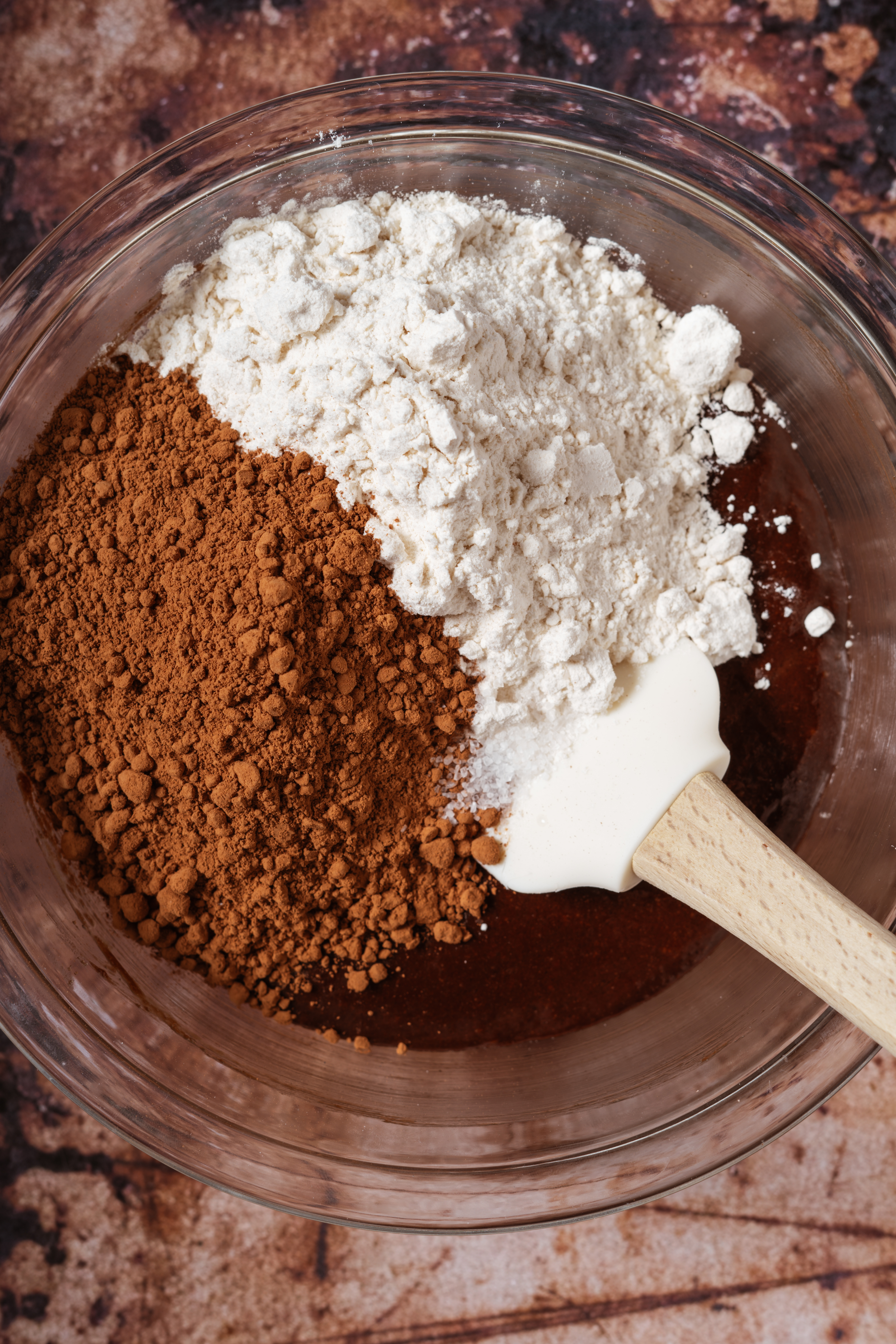 dry ingredients and brownie batter in glass bowl before mixing.