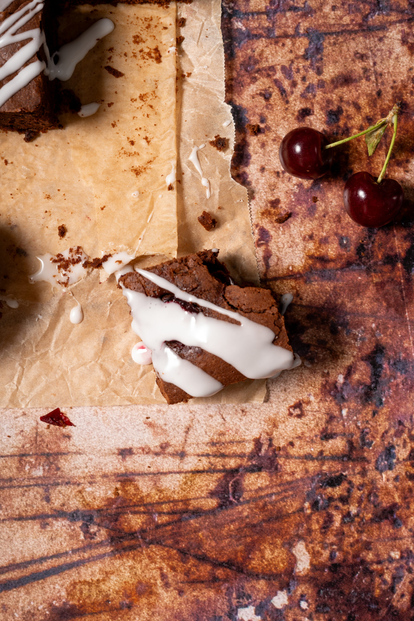 chocolate cherry brownie piece on parchment paper with cherries.