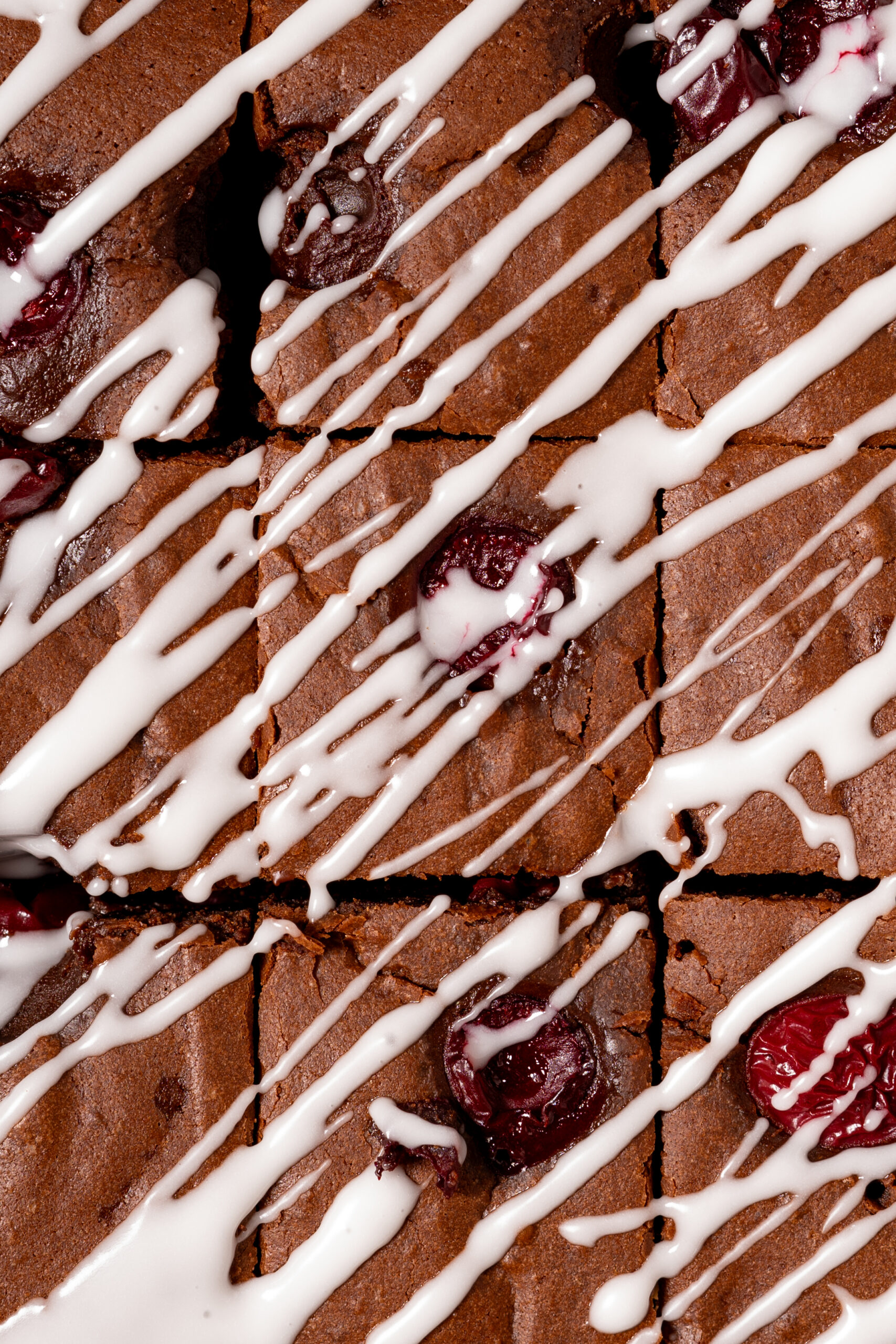 close up of chocolate cherry brownies with icing drizzle.