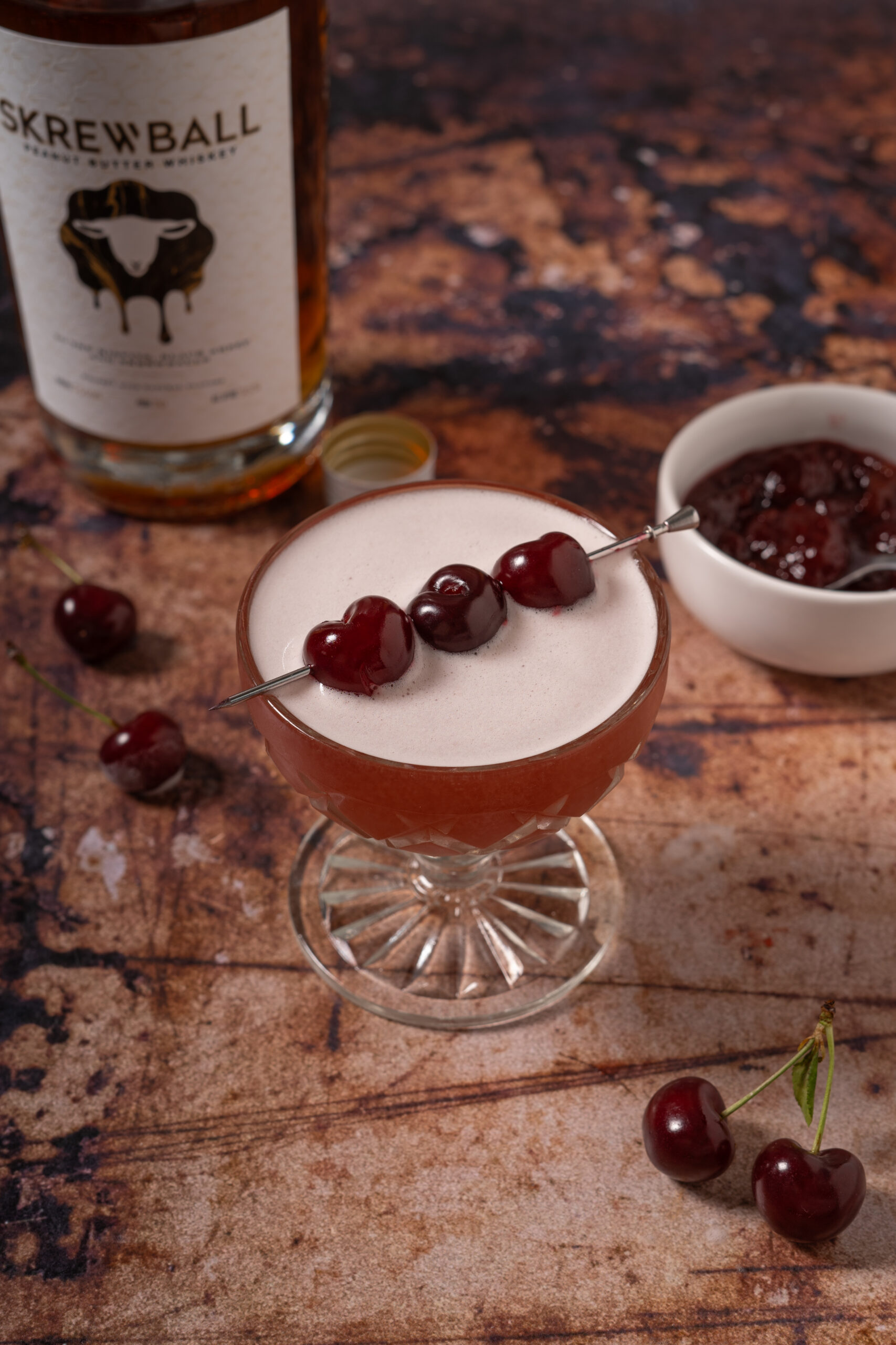 whiskey sour with cherry garnish in coupe glass.