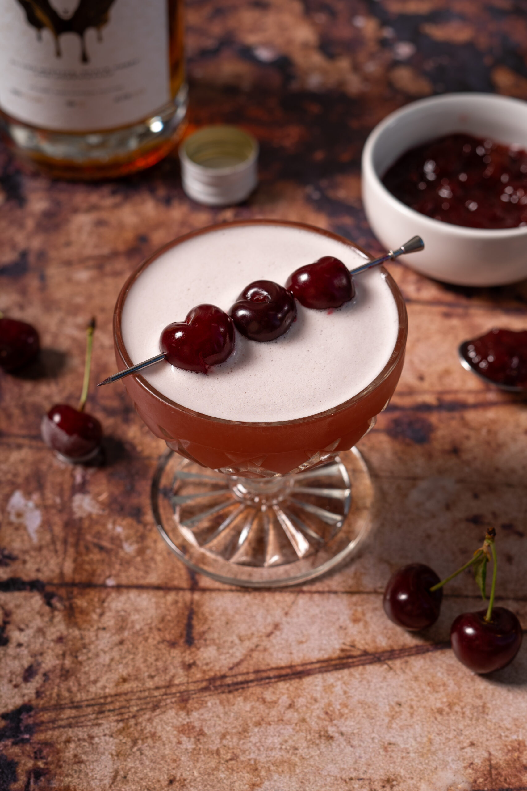 whiskey sour with cherry garnish in coupe glass.