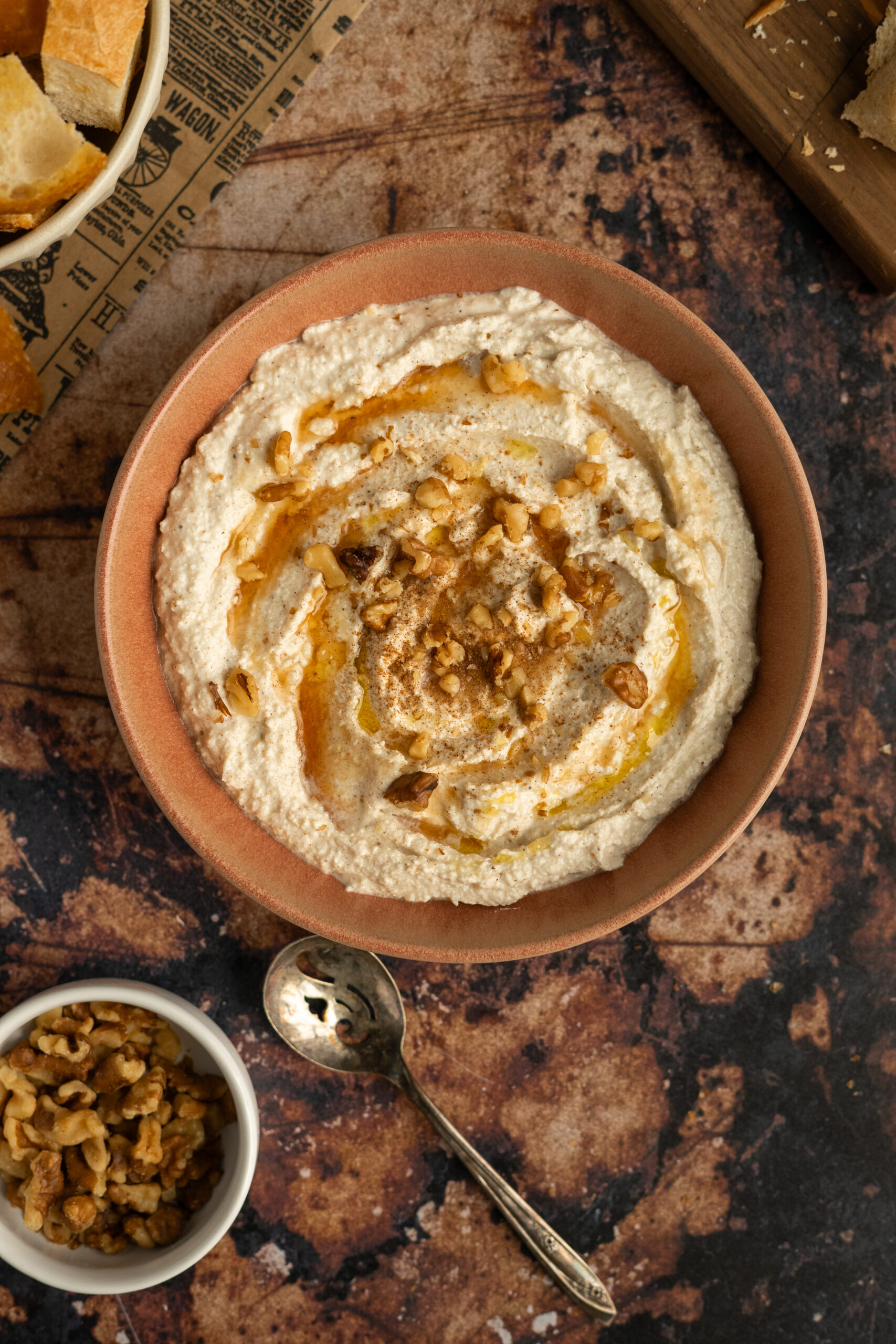 whipped feta dip in pink bowl with syrup and walnuts.