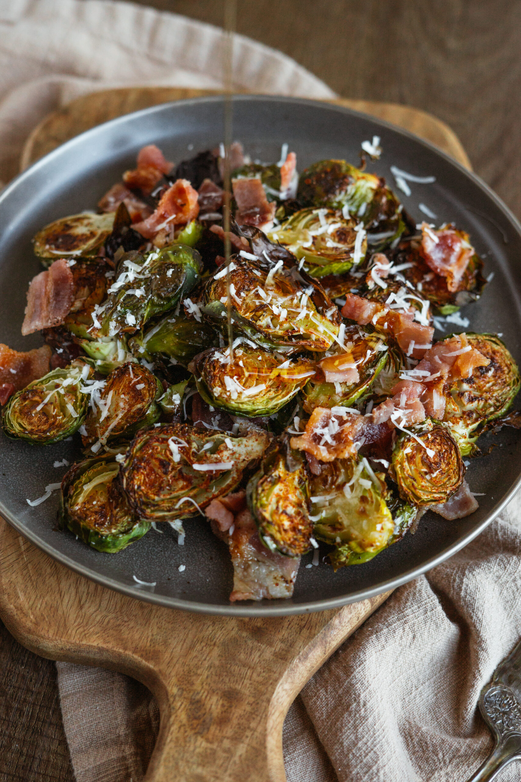 maple bacon brussels sprouts on dark plate with syrup poured on.