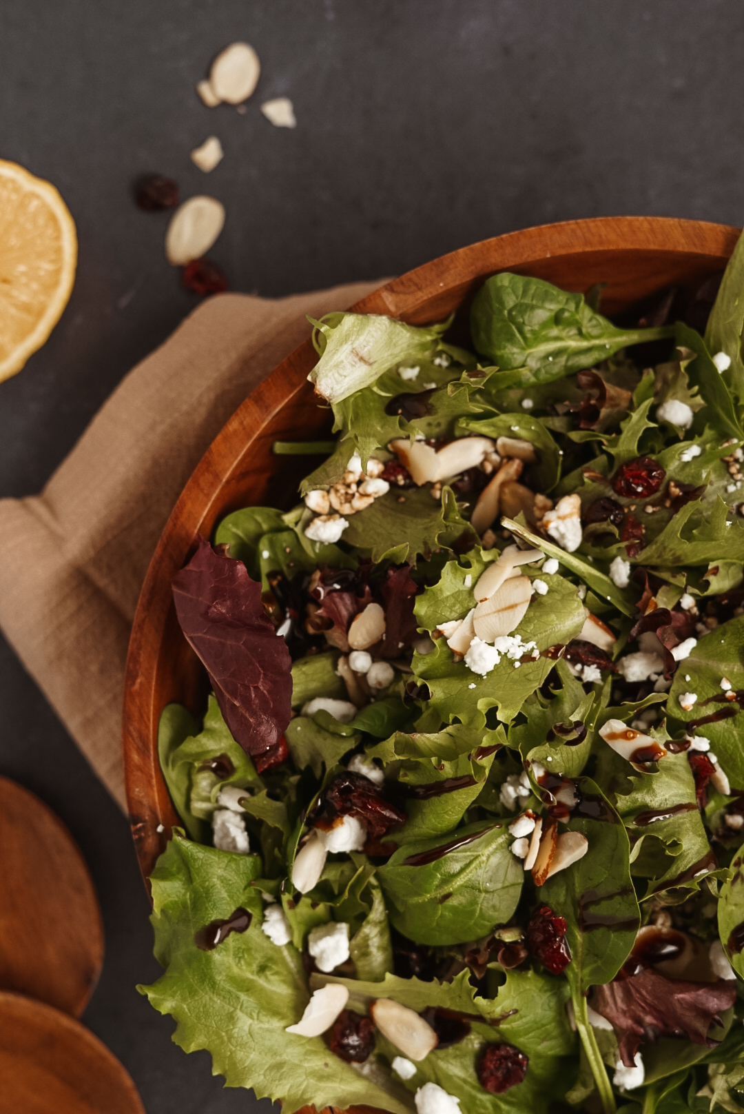 close up of cranberry goat cheese salad in wooden bowl on black background.