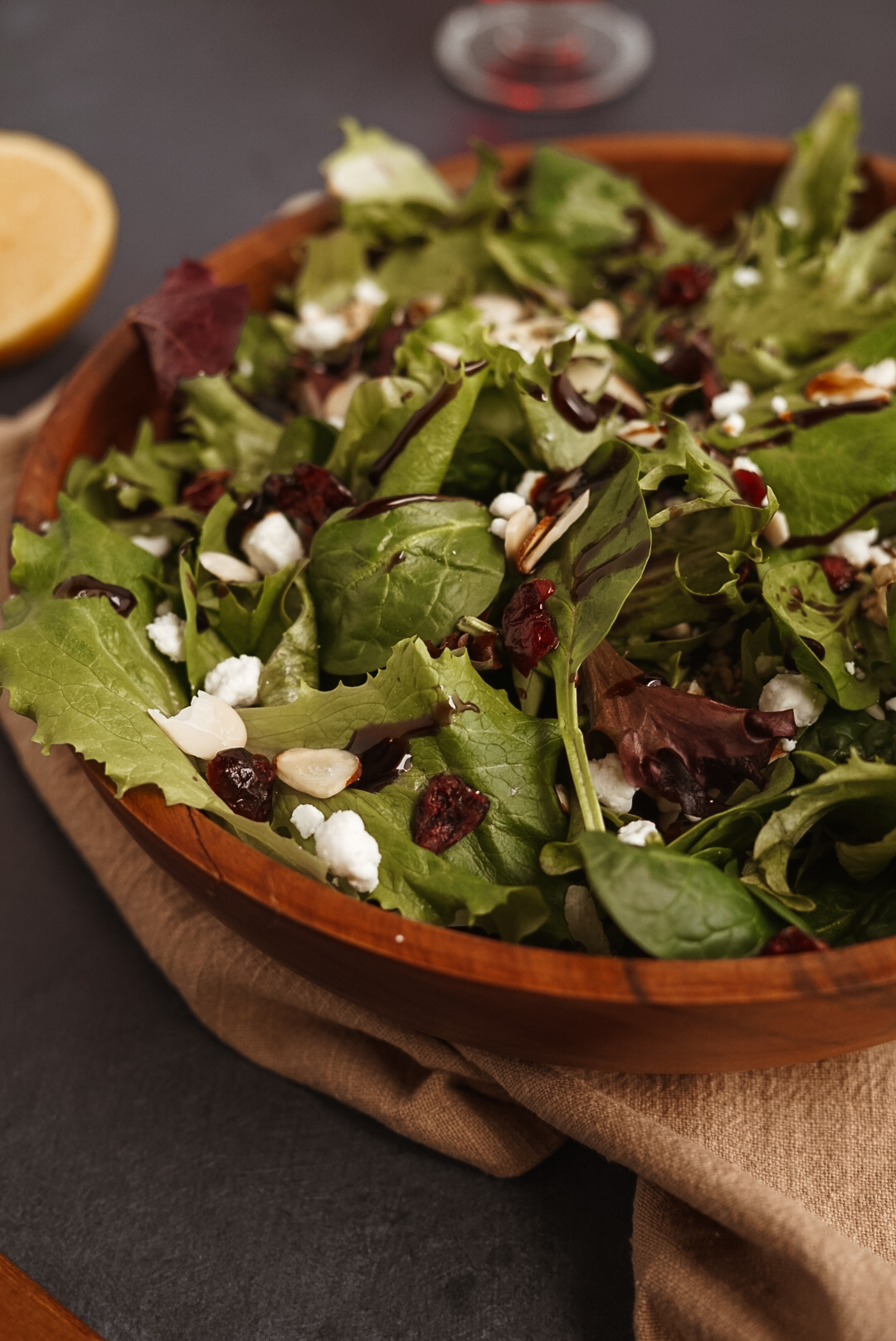 side view of cranberry goat cheese salad in wooden bowl on black background.