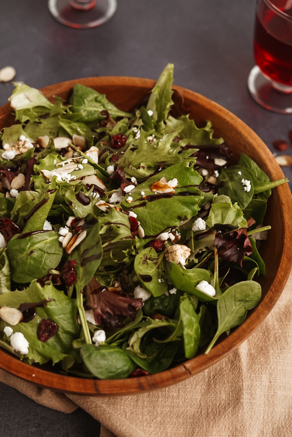 cranberry goat cheese salad in wooden bowl on brown linen napkin.