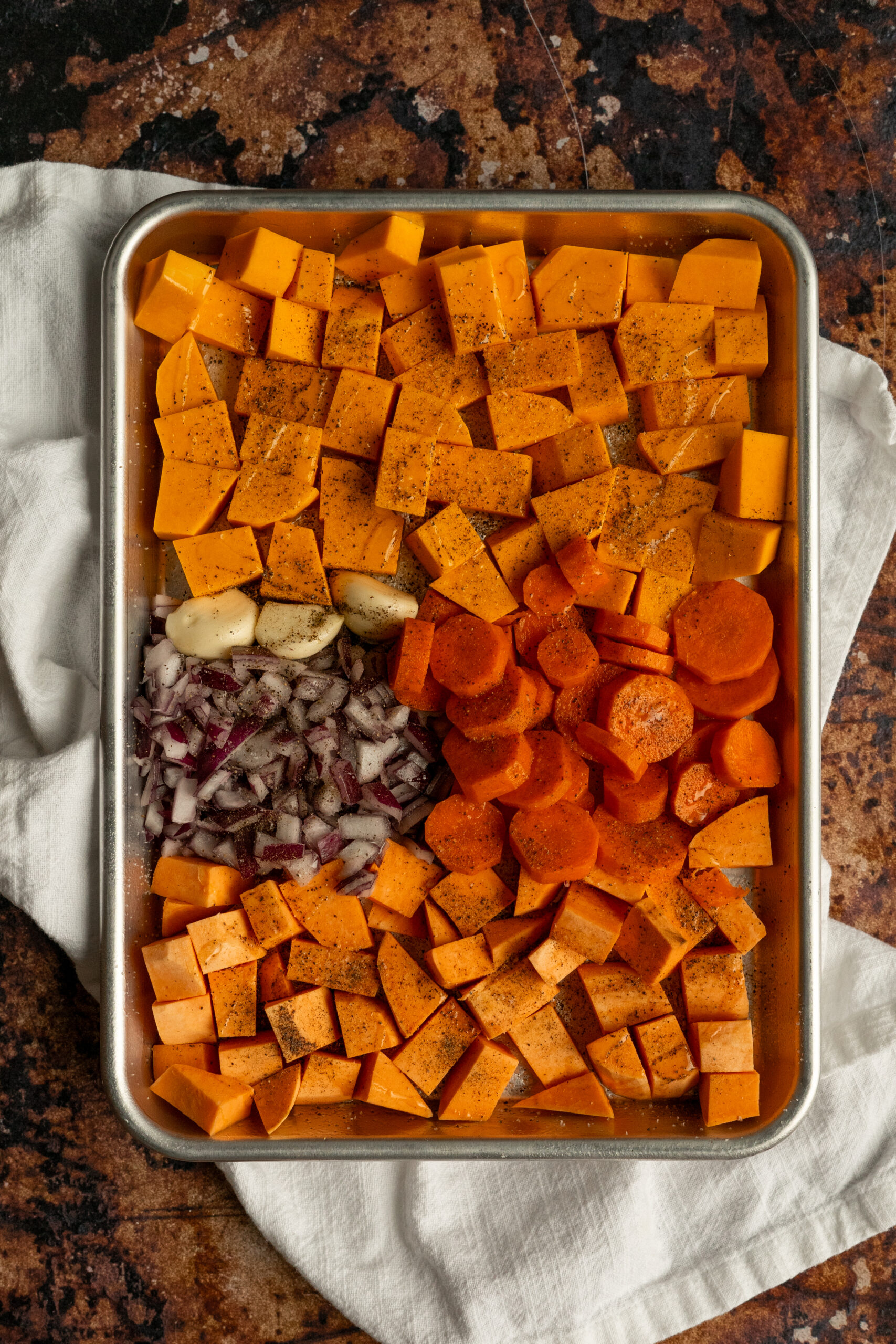 tray of cubed vegetables on sheet tray with seasonings sprinkled on.