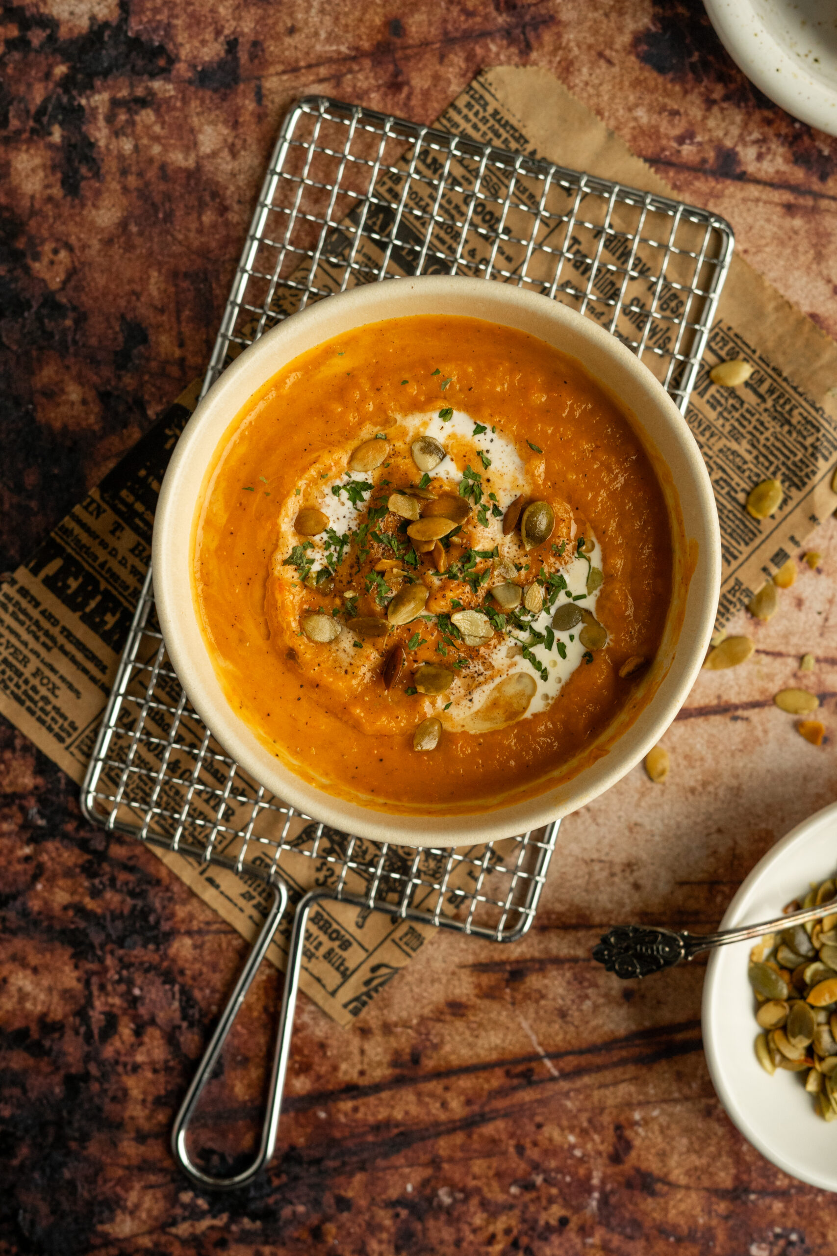 roasted vegetable soup in white bowl with roasted seeds on top.