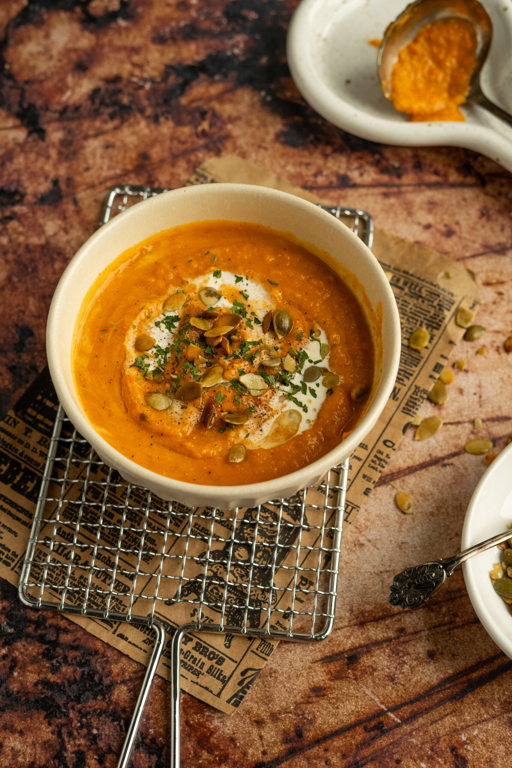 roasted vegetable soup in white bowl with roasted seeds on top.