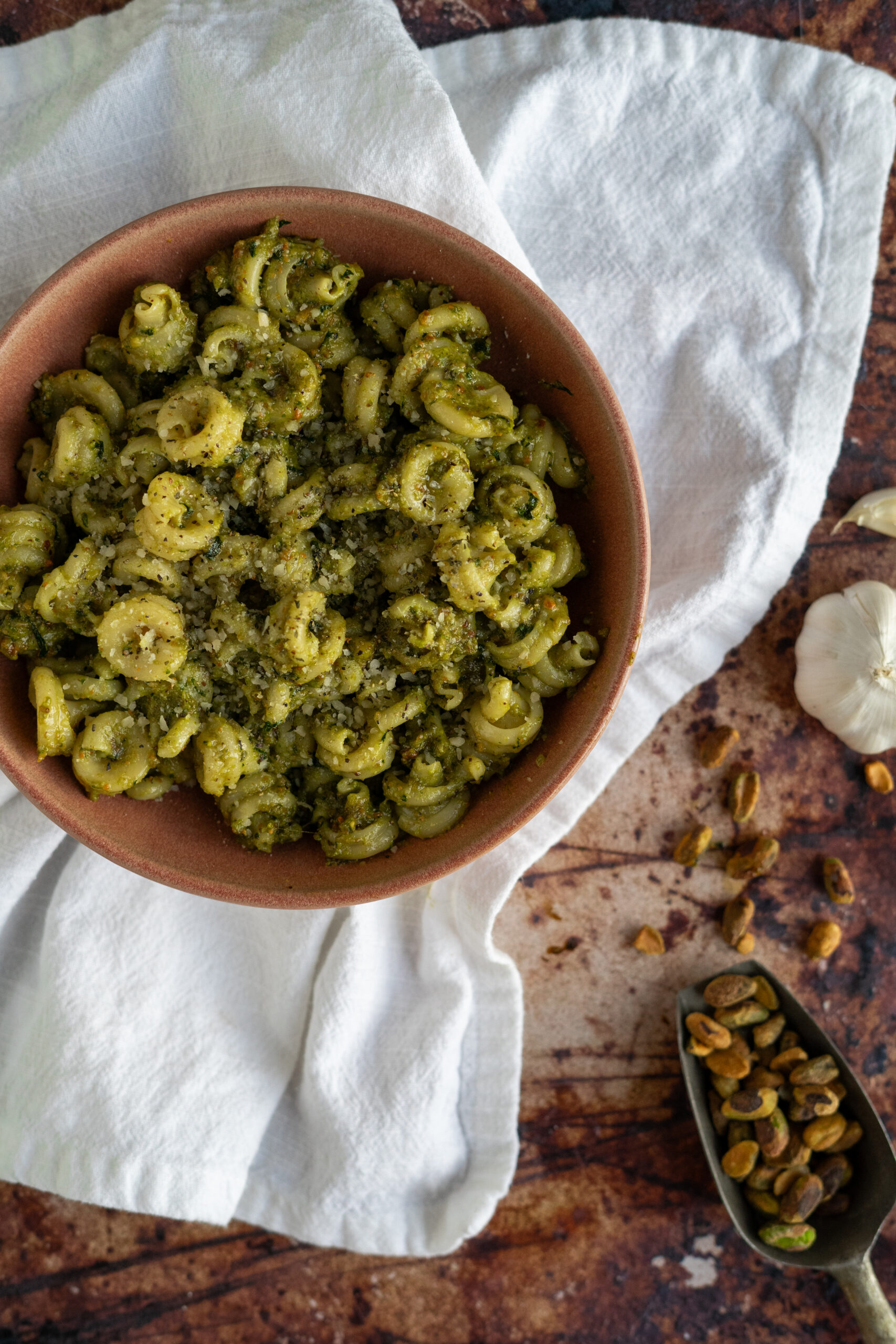 pistachio pesto pasta in pink bowl on white napkin.