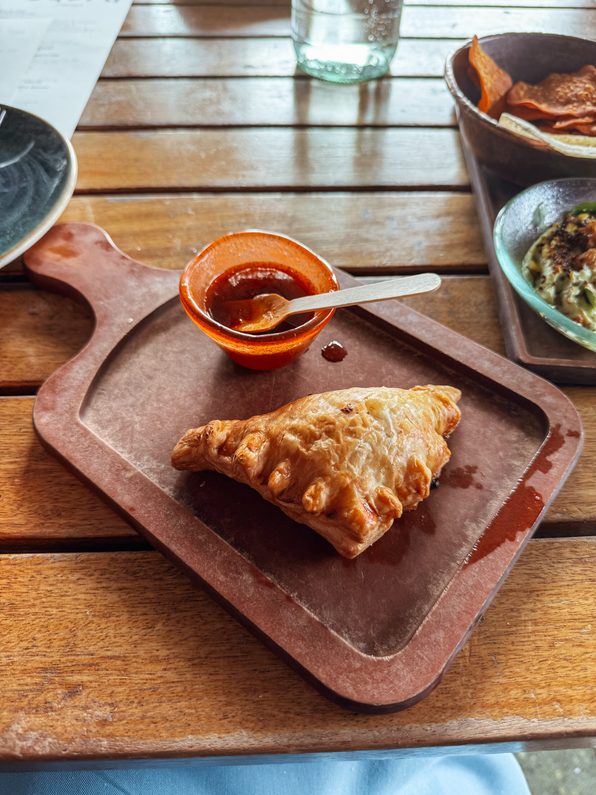 empanada and sauce on wooden tray.