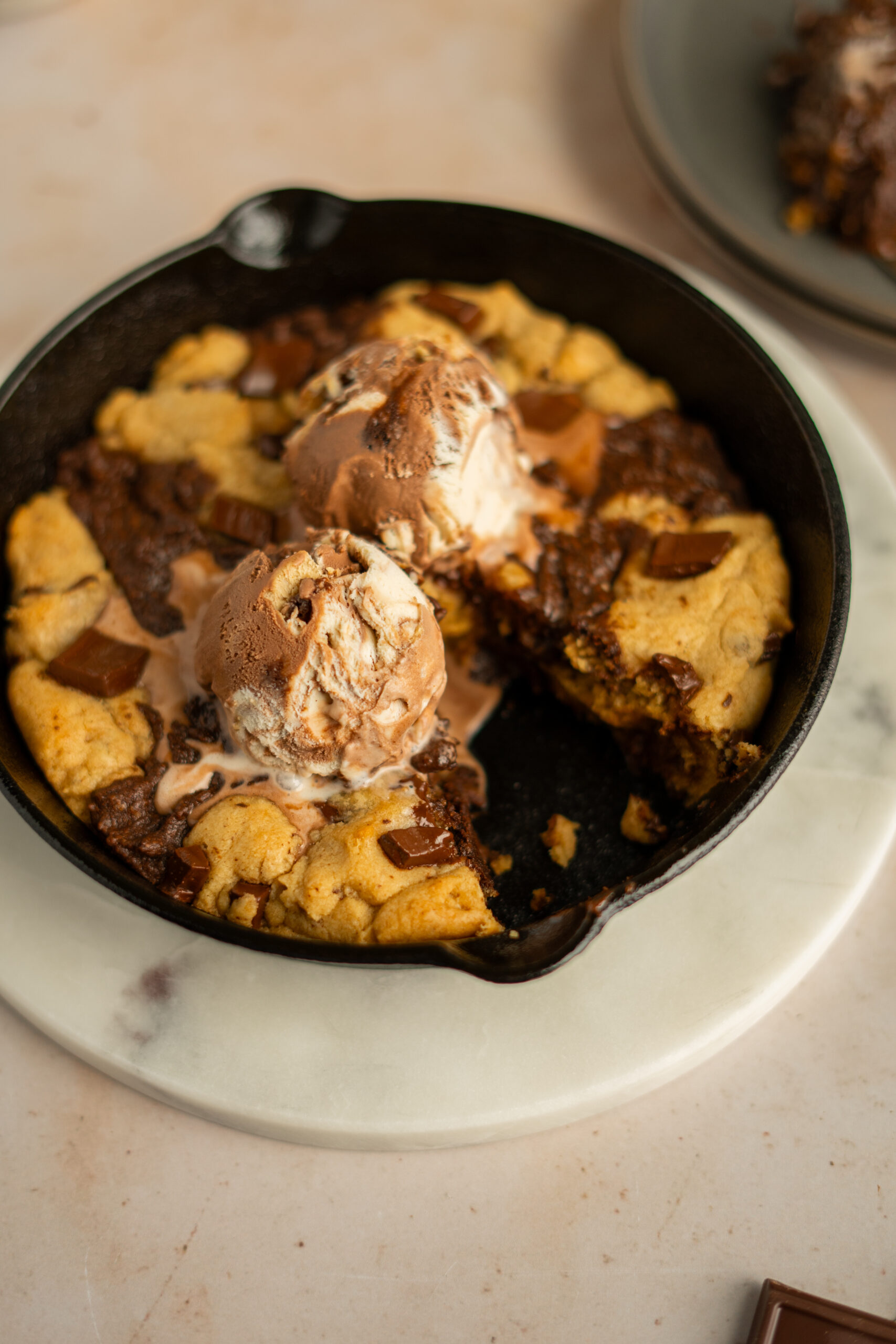 brownie skillet cookie with ice cream on top and slice taken out of the side.