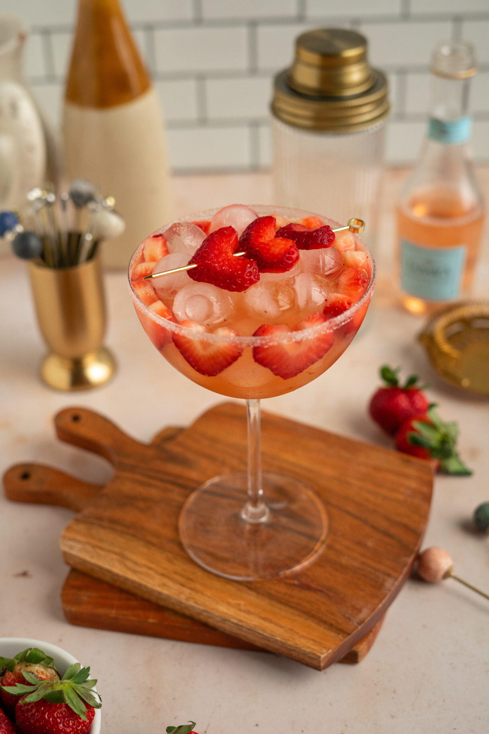 pink strawberry cocktail in coupe glass on stacked wooden coasters.