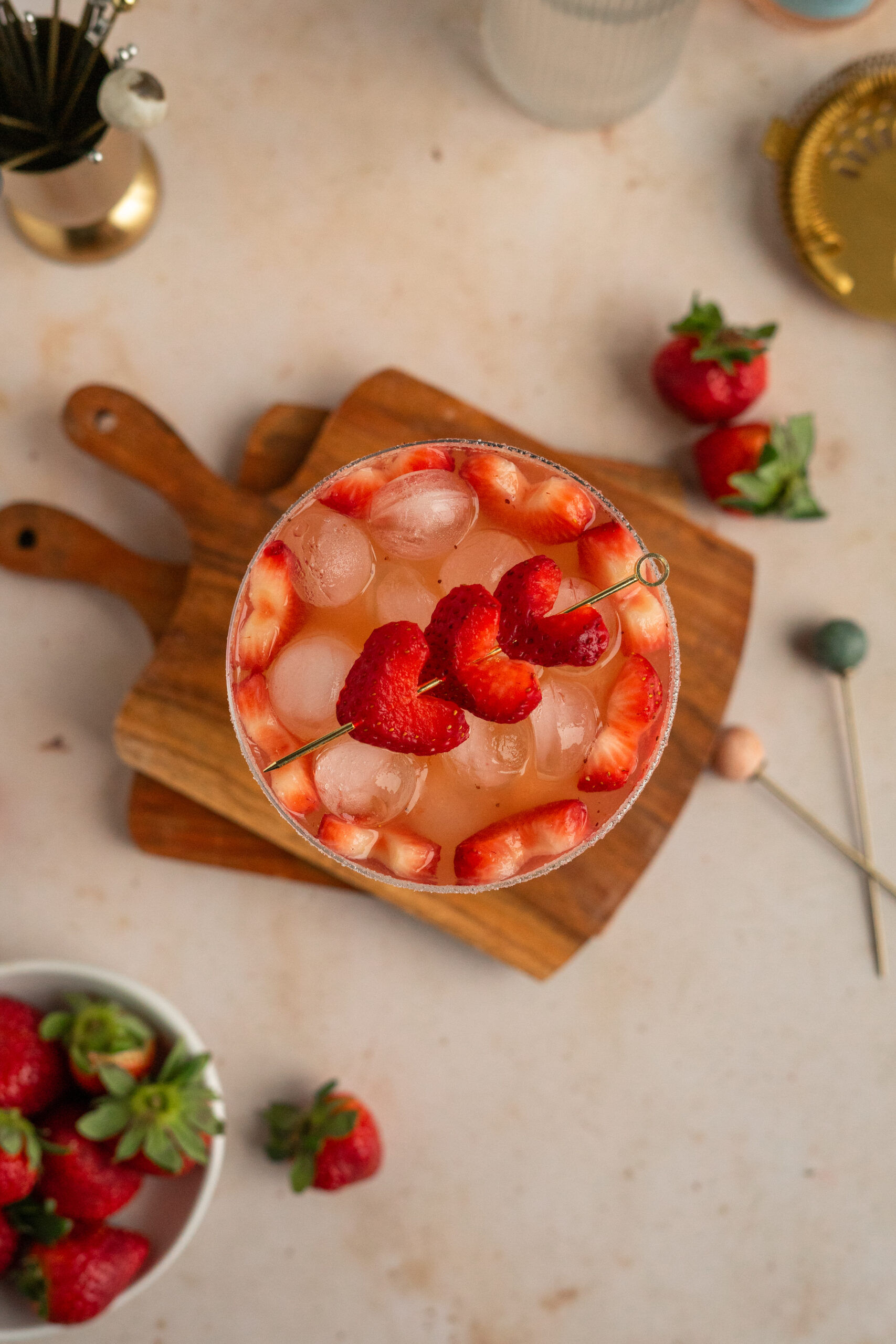 overhead shot of pink strawberry cocktail in coupe glass with strawberry heart garnish.