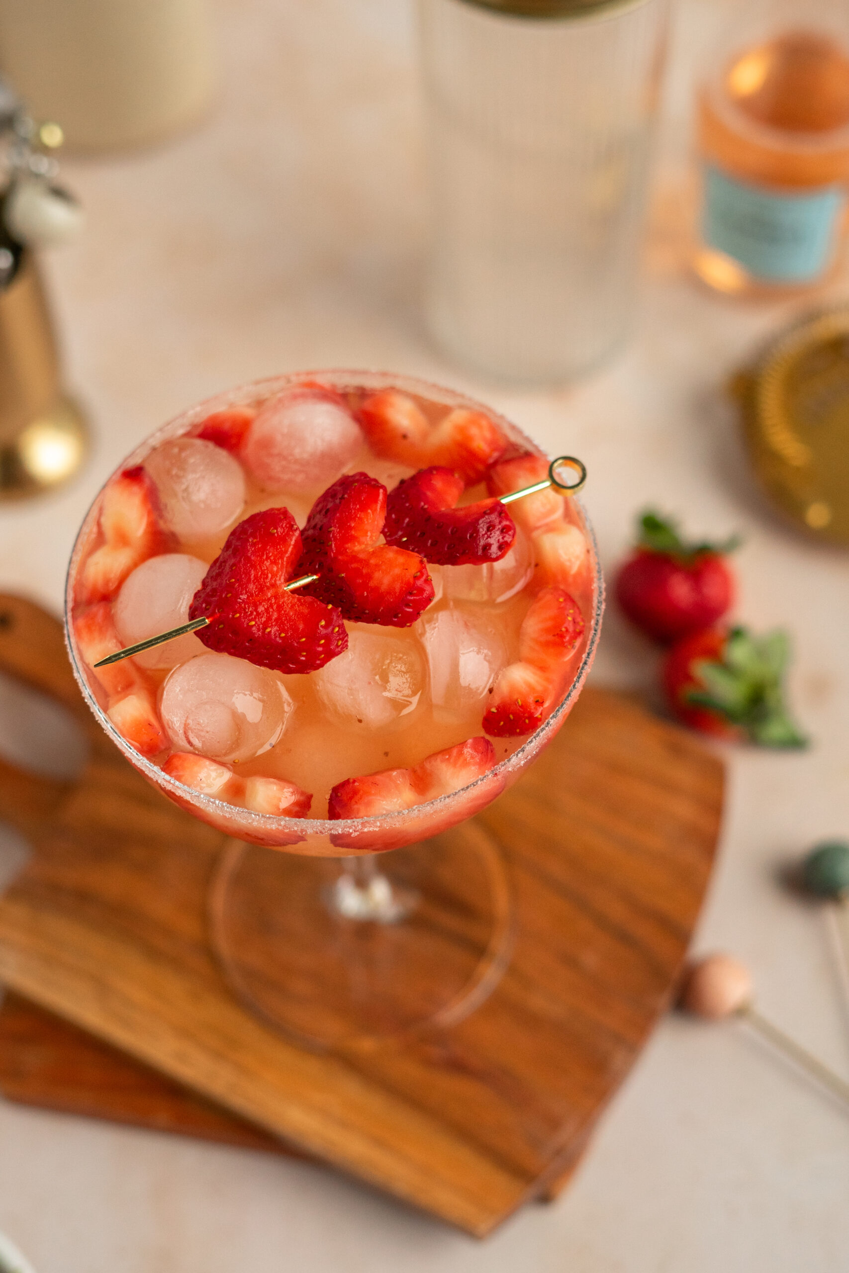 overhead shot of pink strawberry cocktail in coupe glass with strawberry heart garnish.