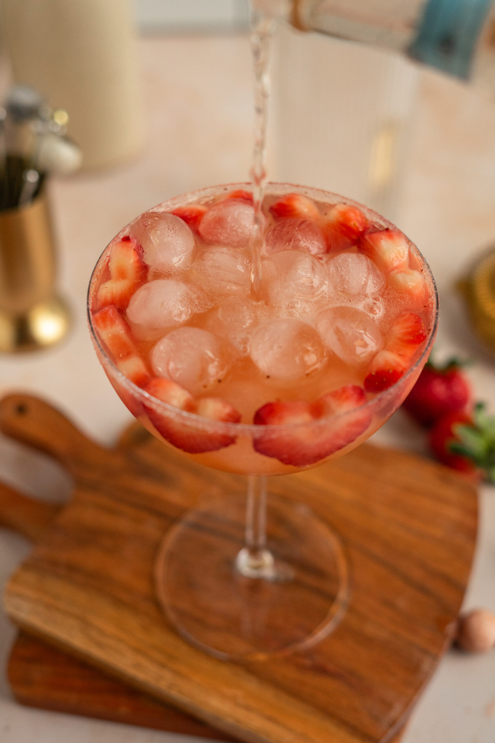 overhead shot of Prosecco poured into pink strawberry cocktail in coupe glass.