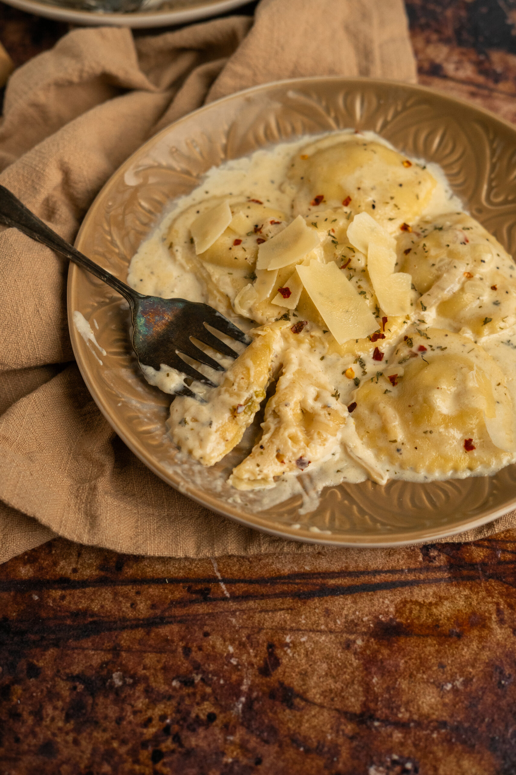 ravioli in white wine sauce on brown plate with bite taken out of one ravioli.