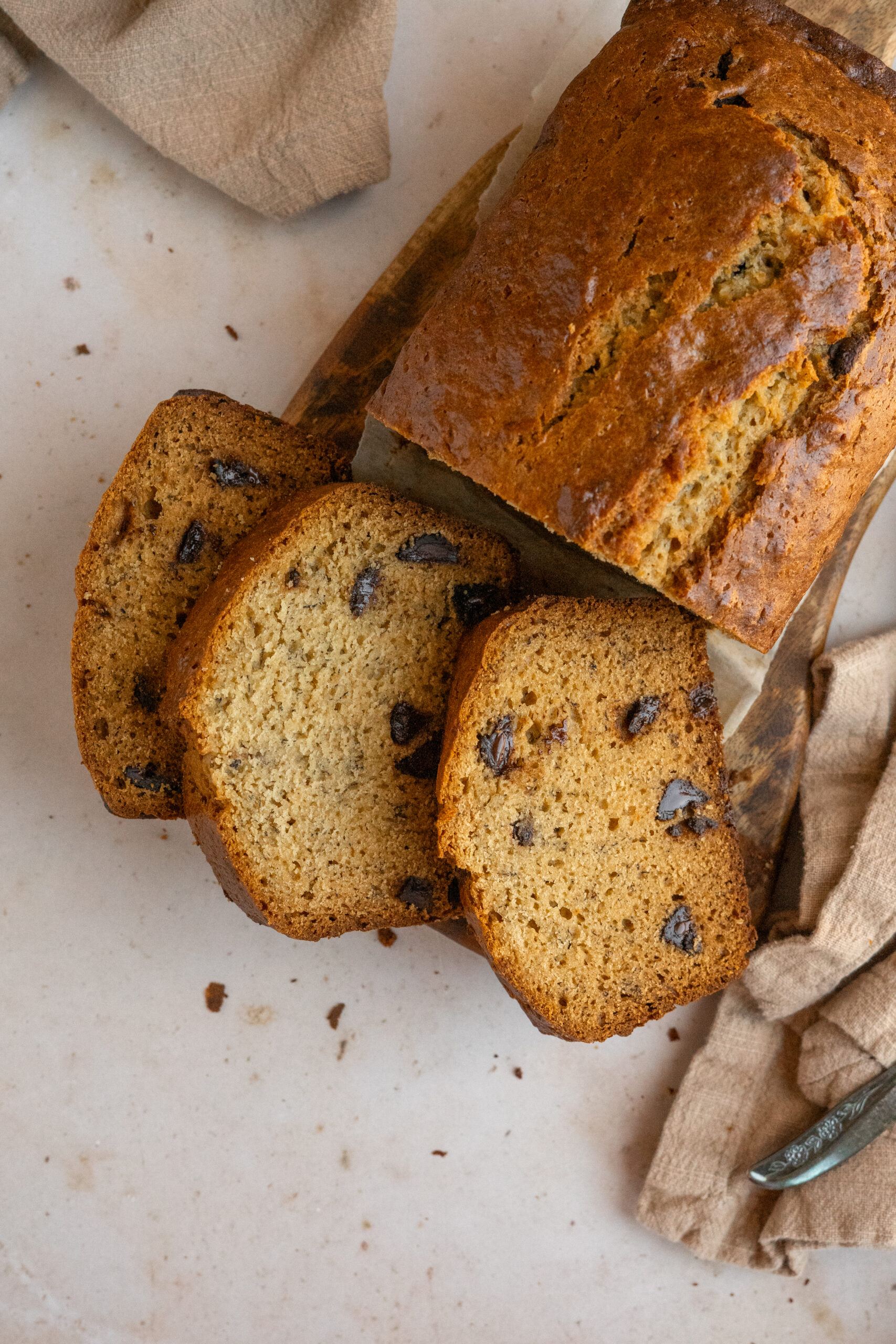 overhead view of banana bread slices on wooden board.