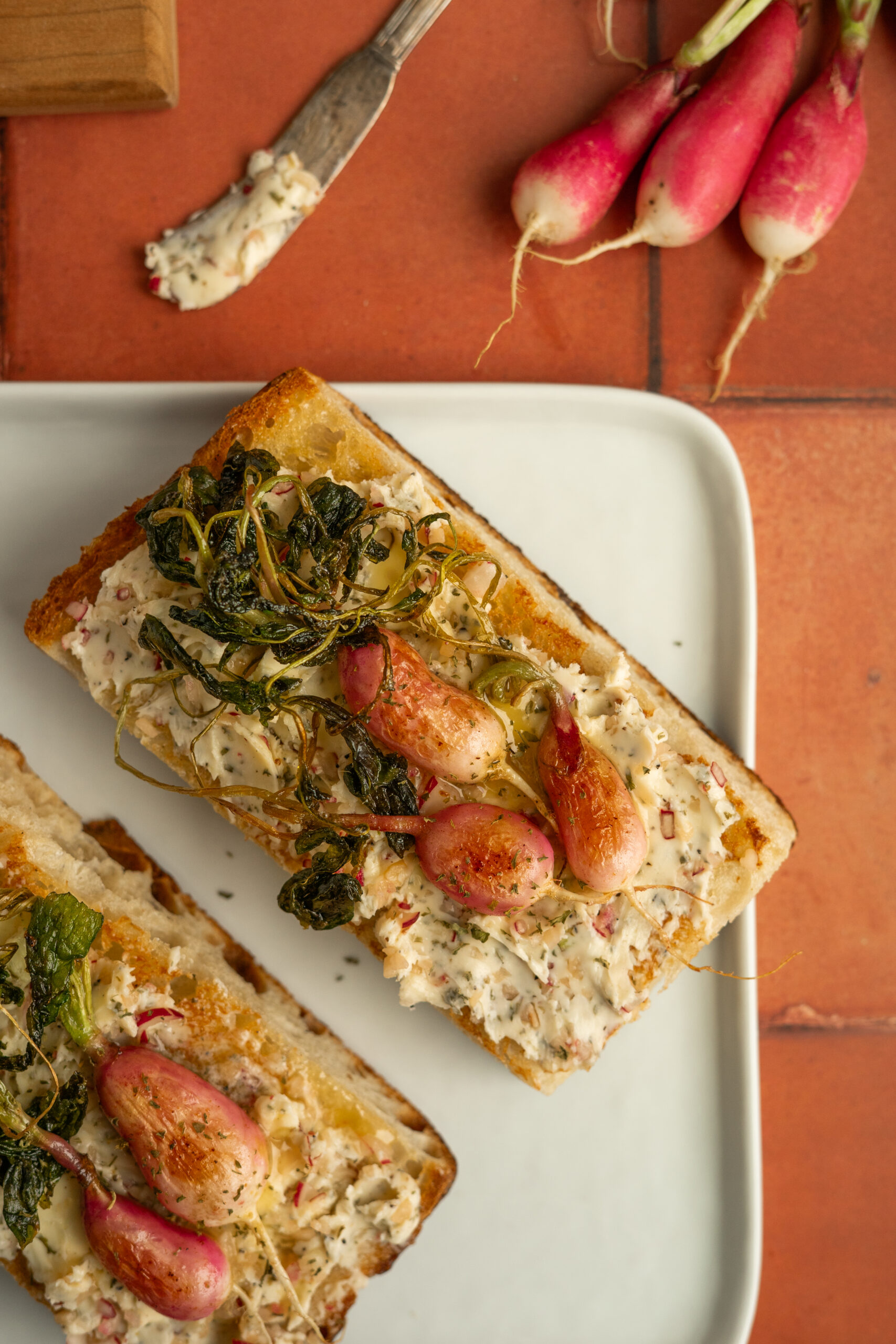 toasted focaccia with radish butter and roasted radishes on top.
