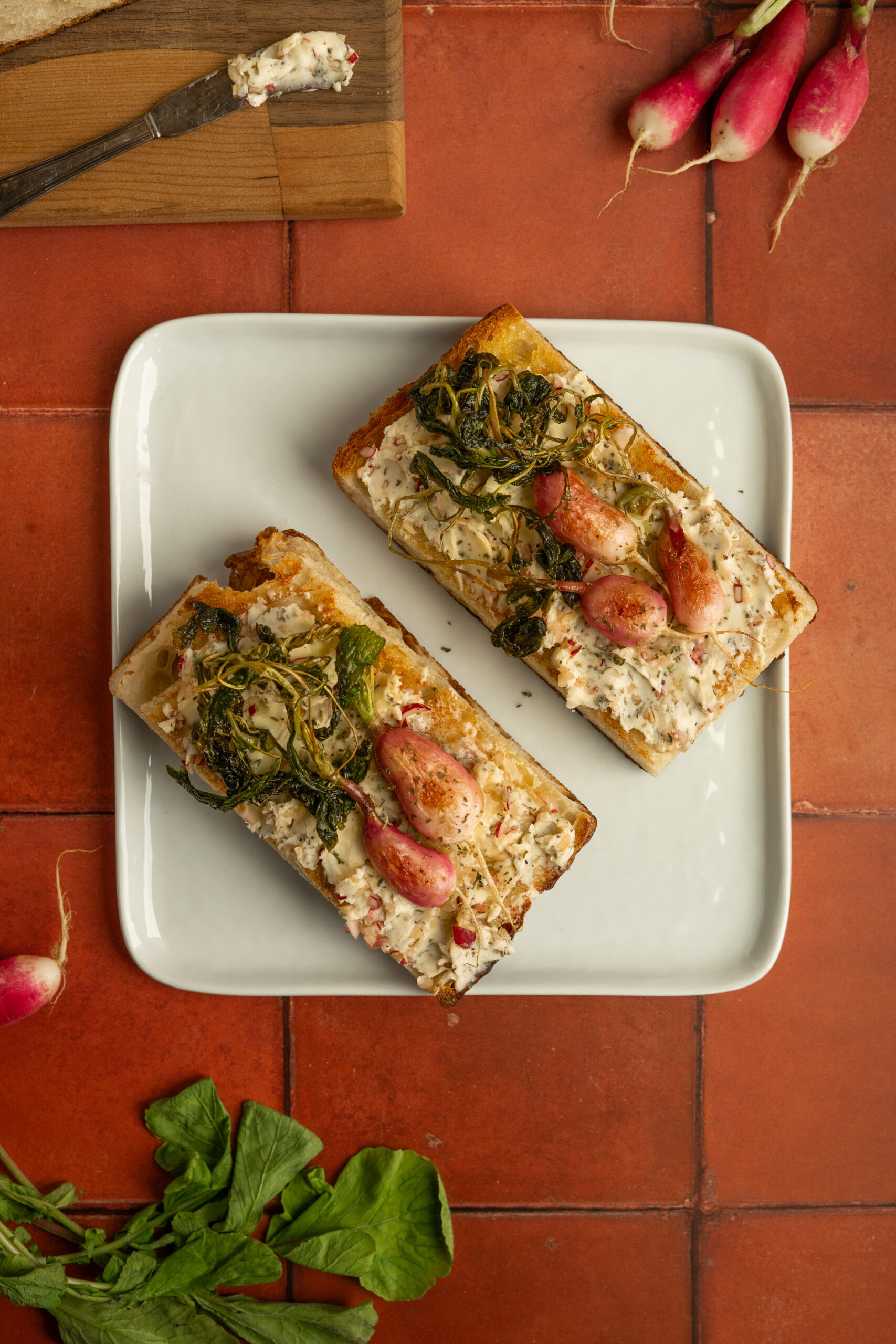 overhead view of toasted focaccia with radish butter on white plate.