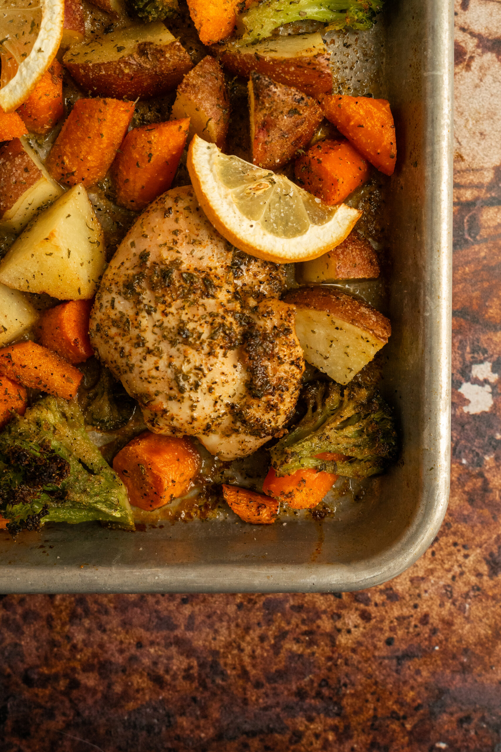 corner view of sheet pan of chicken thighs and roasted vegetables.