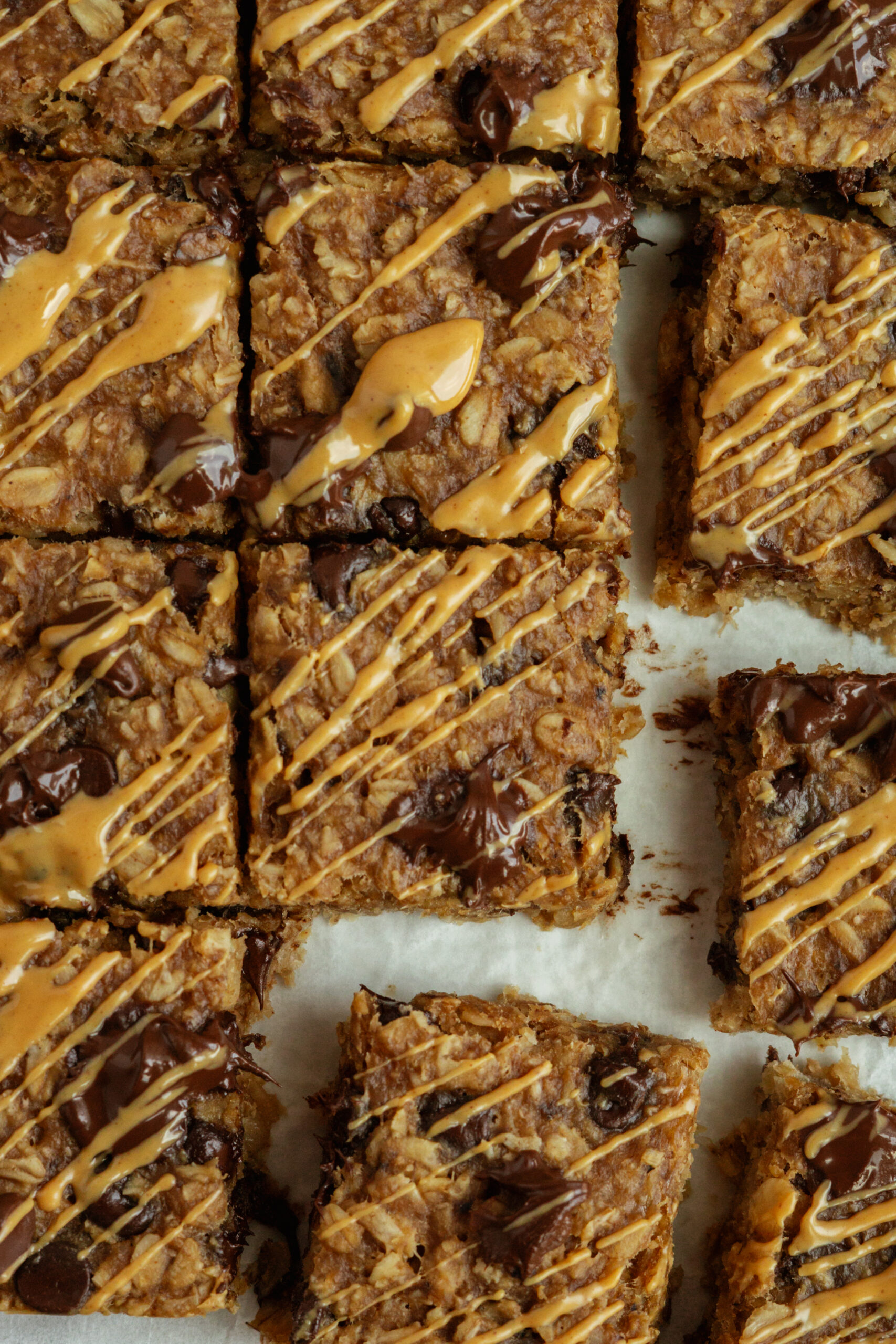 close up of banana oat bars sliced into squares on parchment paper.