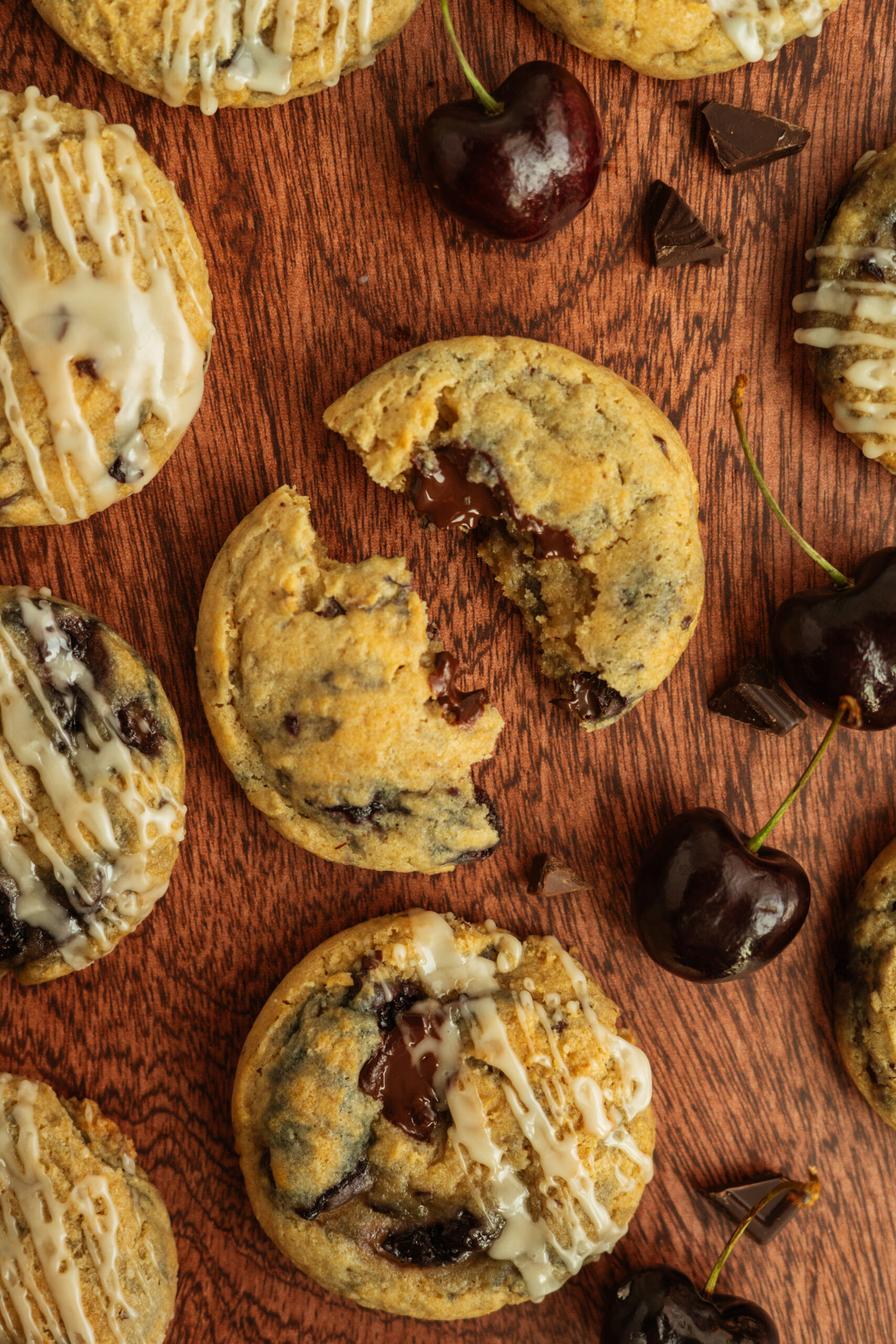 chocolate cherry cookie broken in half on wooden surface.