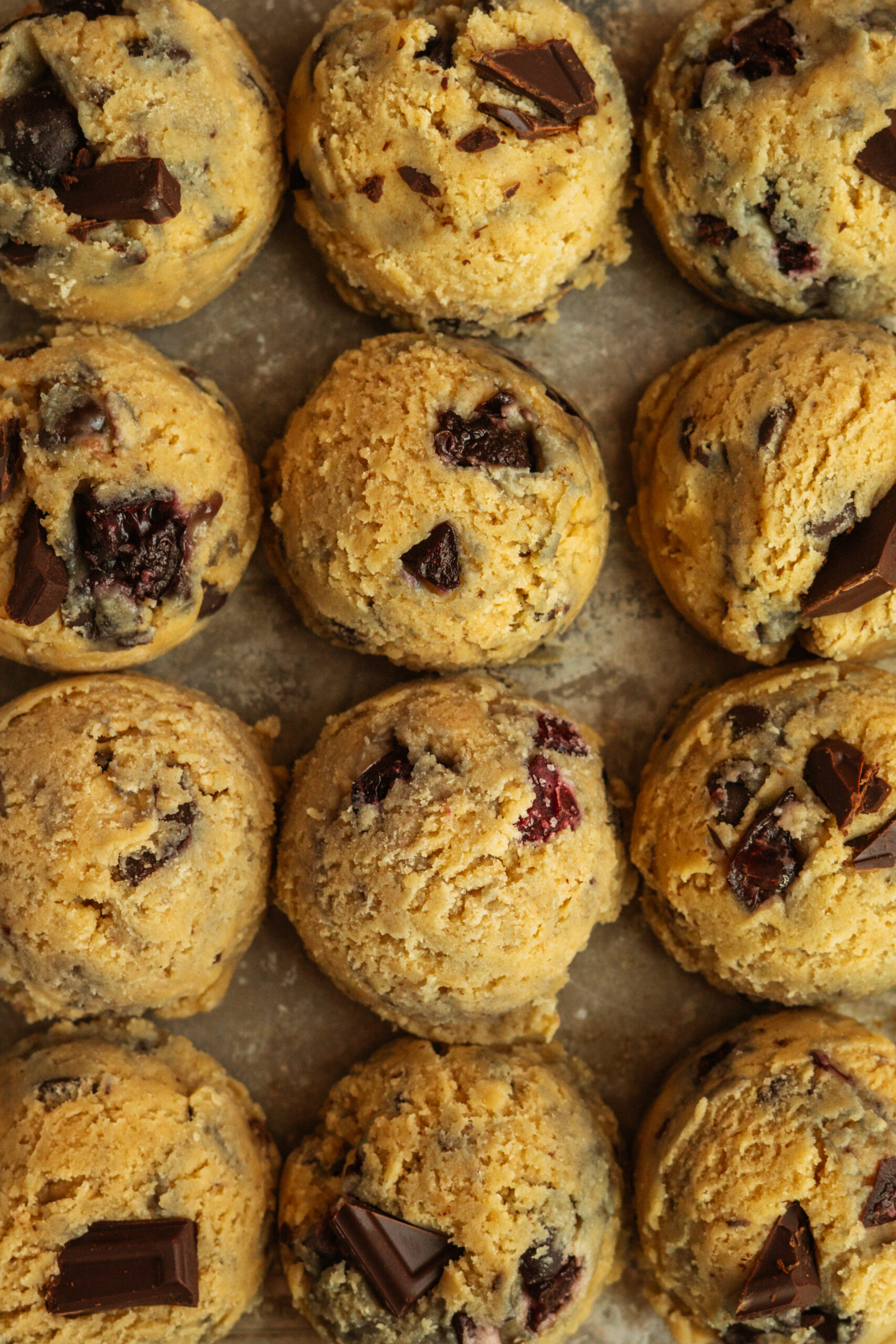chocolate cherry cookie dough scooped into balls and lined up in rows.