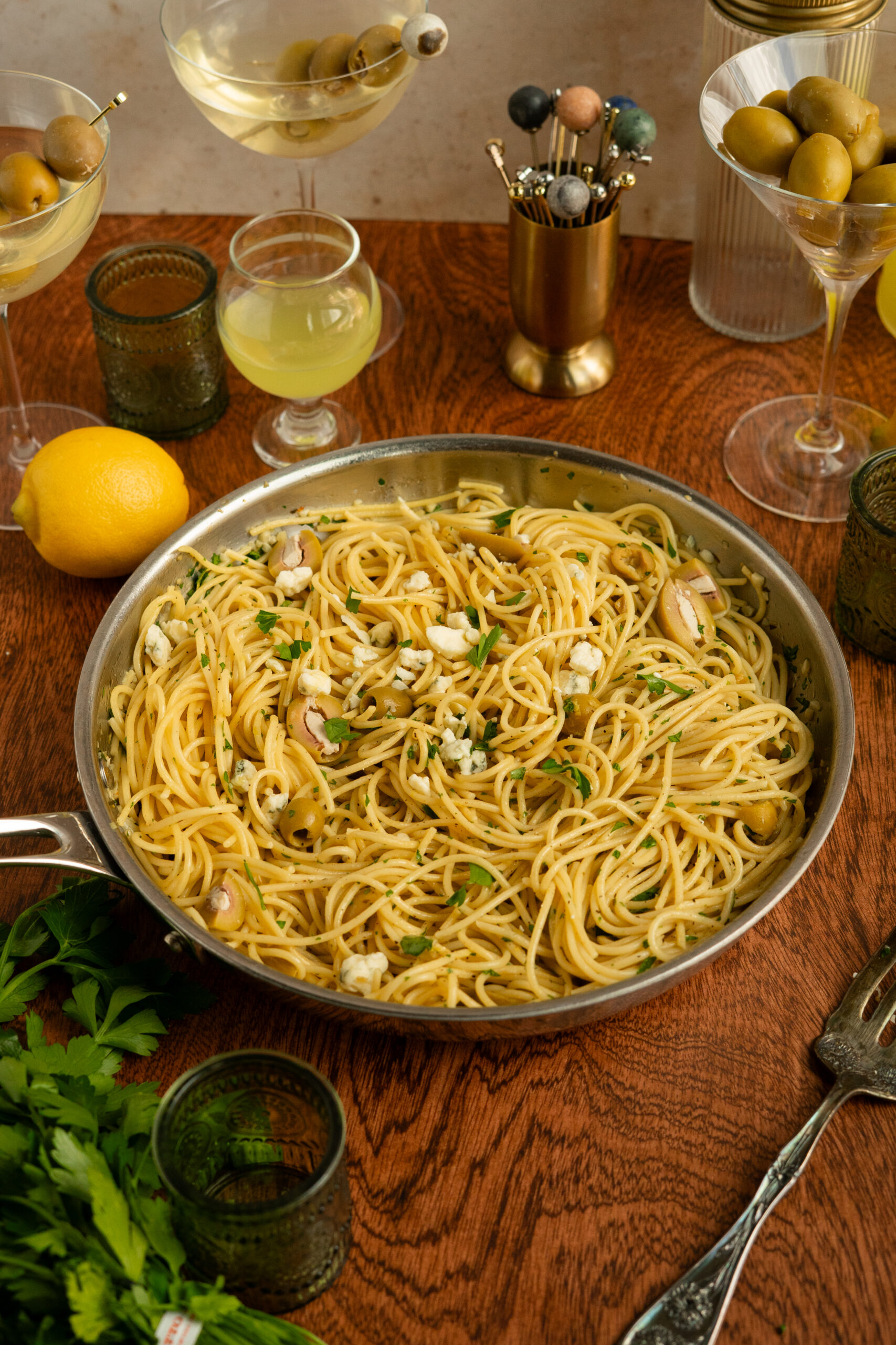 dirty martini pasta in large steel pan on wooden surface.