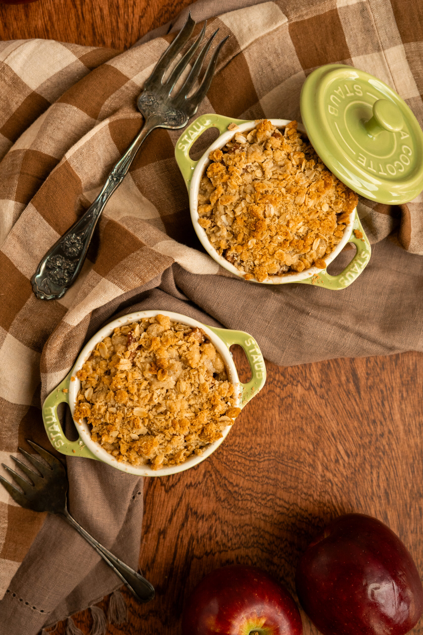 two apple crisps in small dishes on wooden surface.