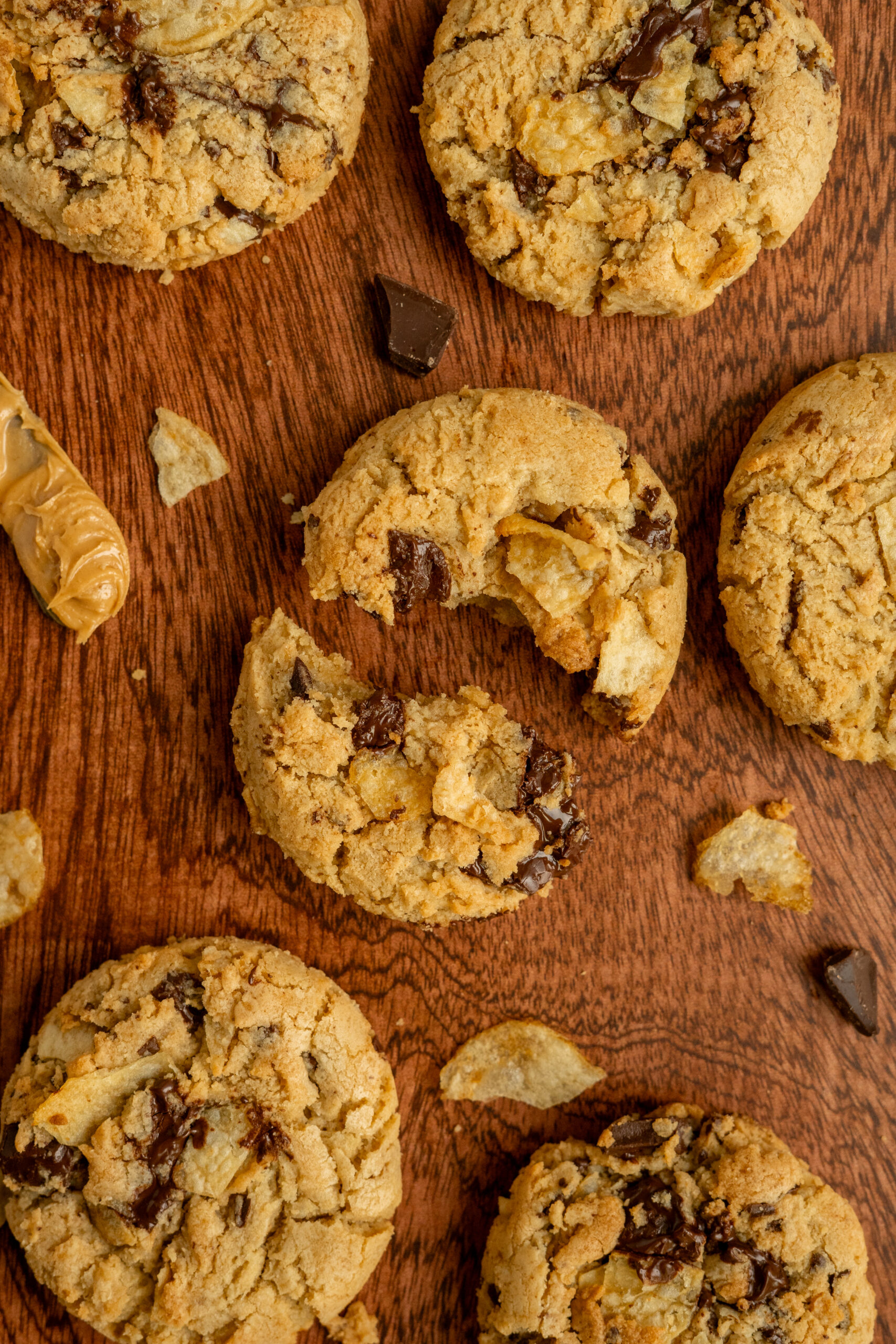 peanut butter chip cookie broken in half on wooden surface.