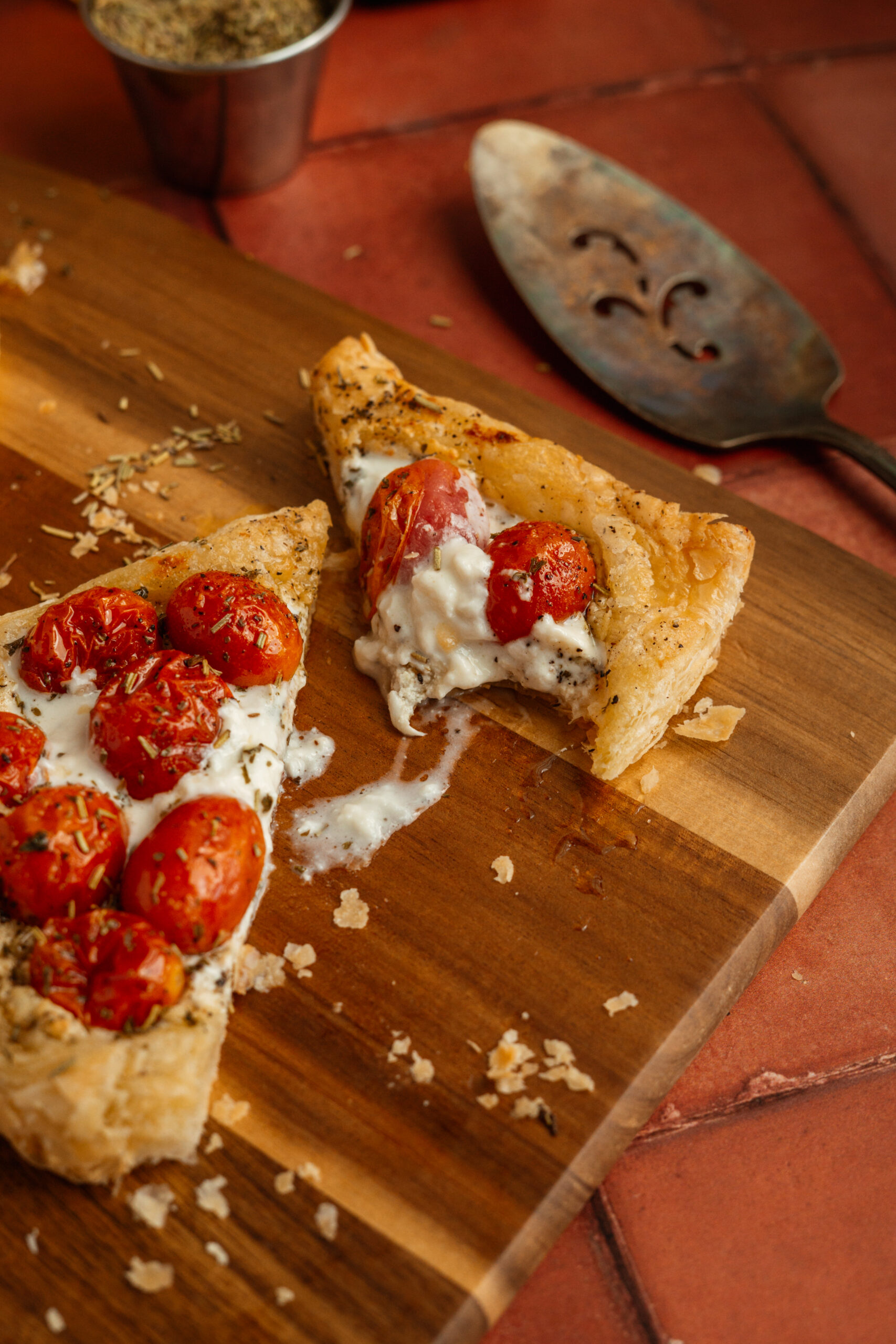 tomato cheese tarts on wooden board with bite taken out of one.