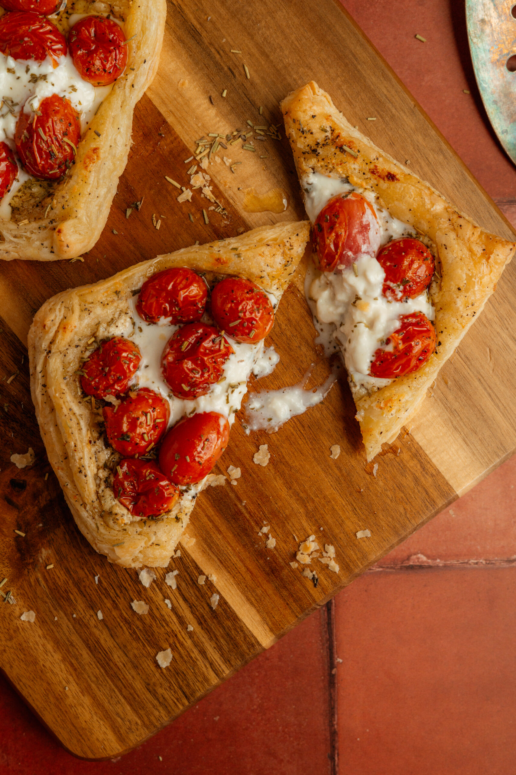 overhead view of sliced tomato cheese tart on wooden board.