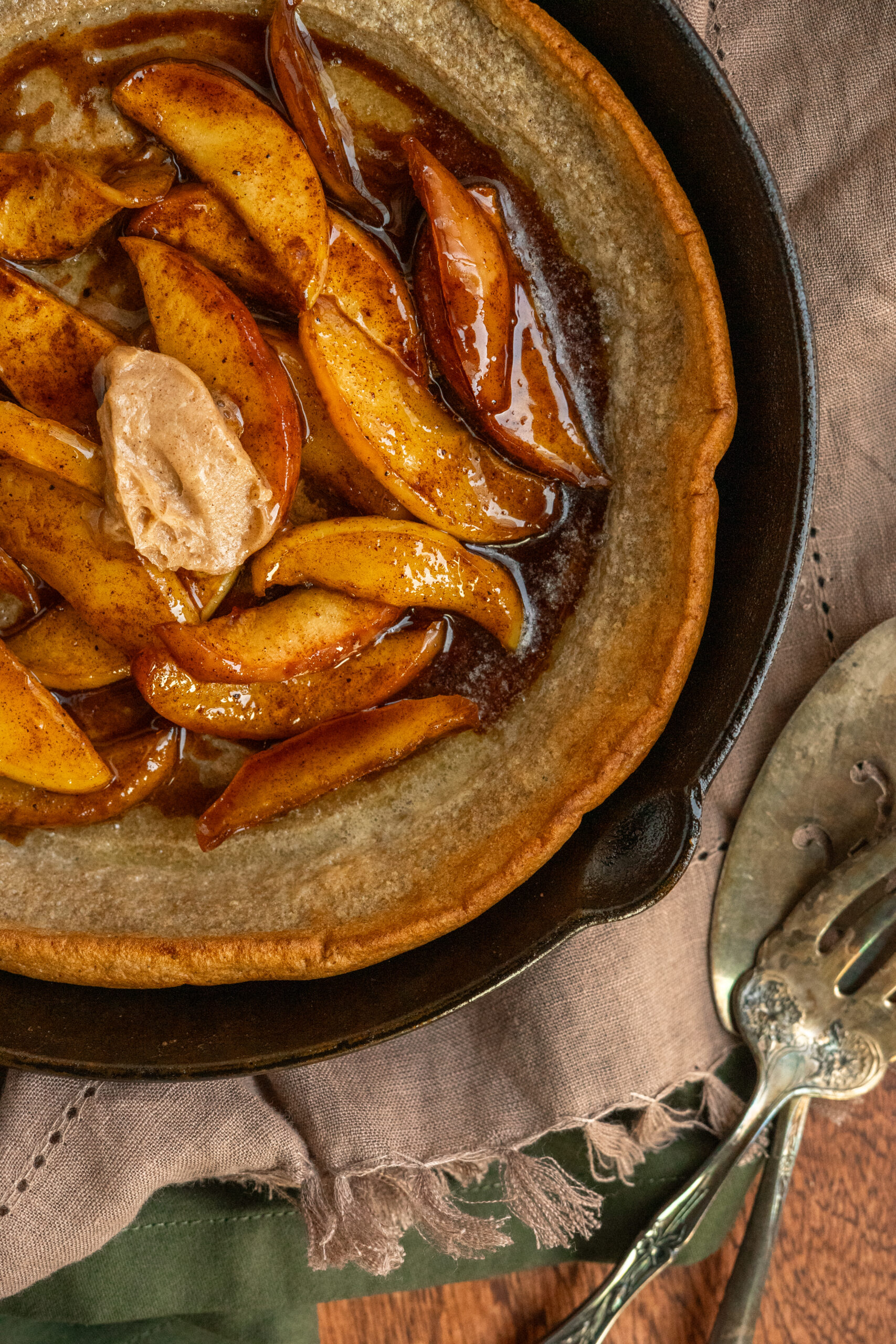 close up overhead view of dutch baby in cast iron pan with baked apples on top.