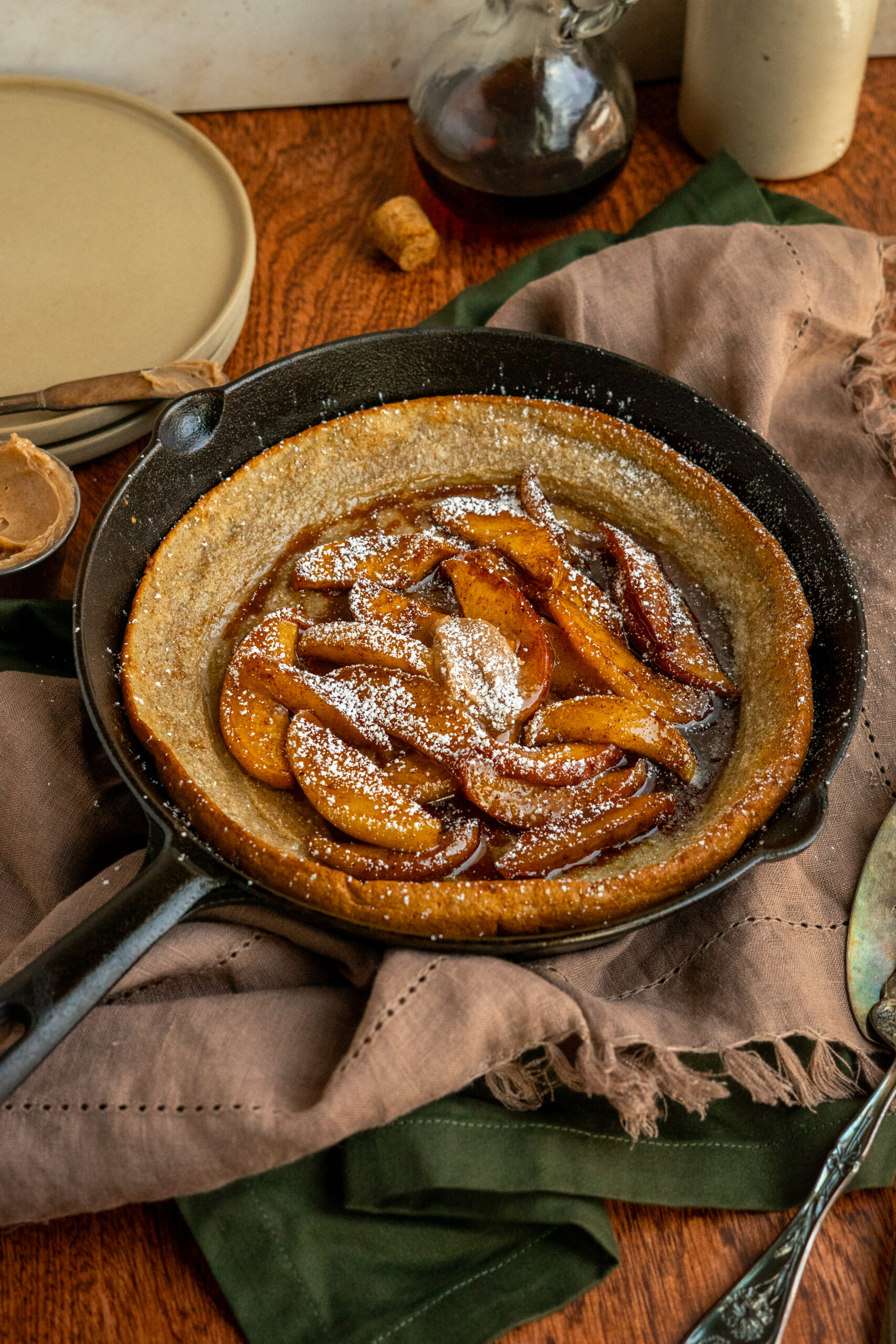 dutch baby in cast iron pan on brown napkin and wooden surface.