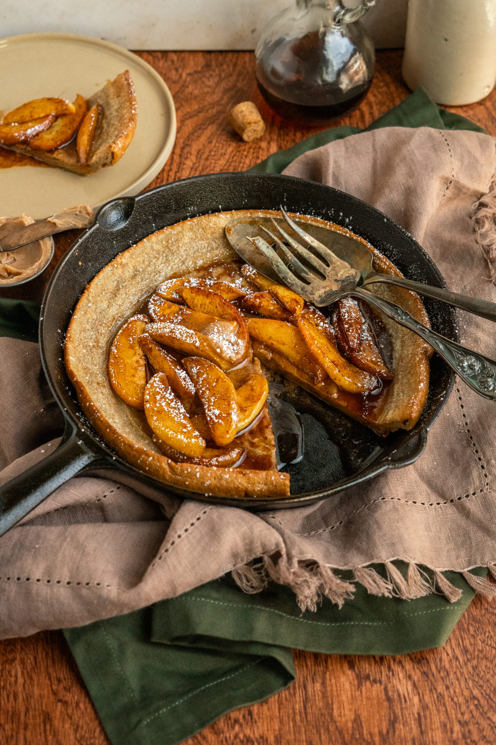 dutch baby in pan on a wooden table with a slice taken out.