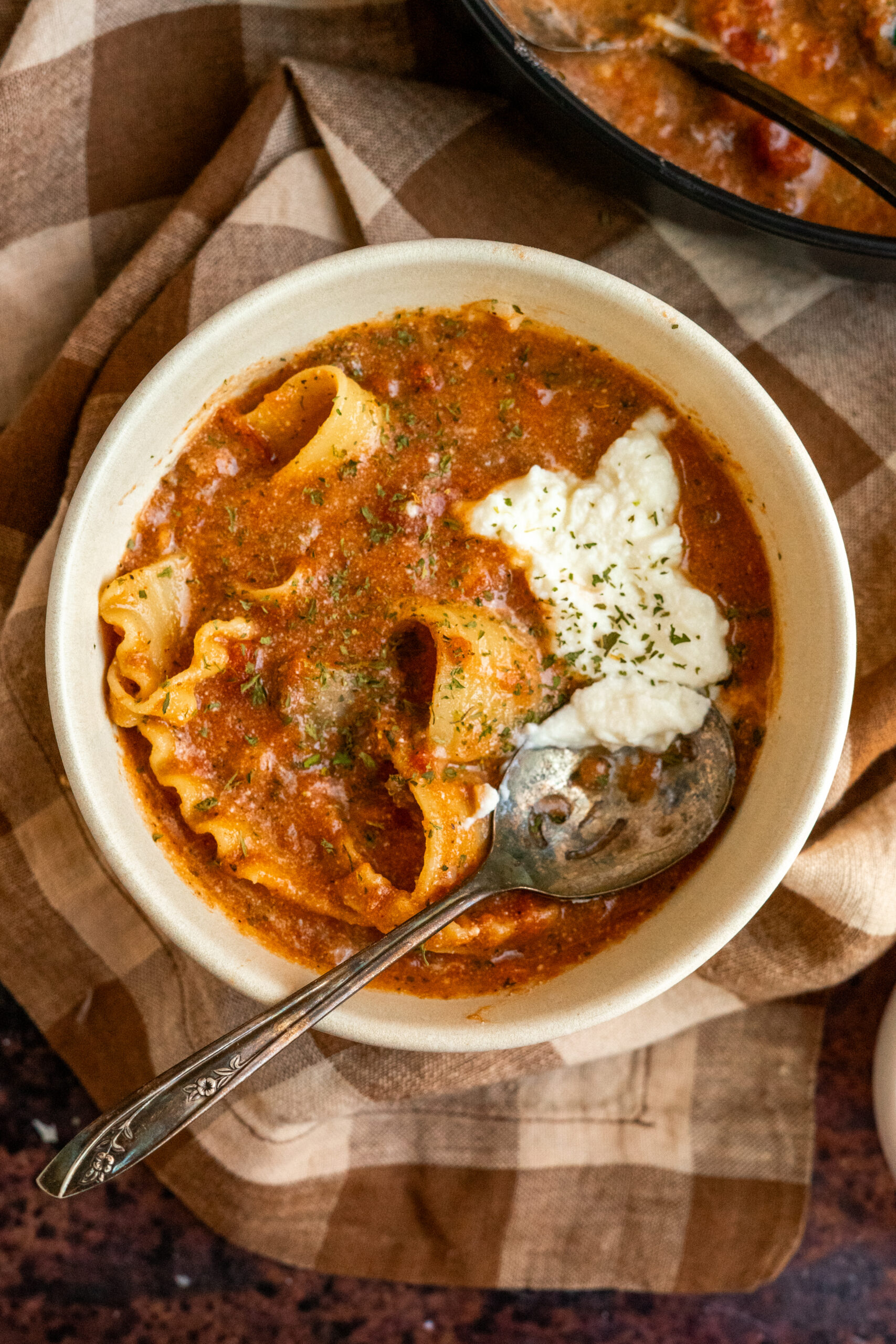 small bowl of lasagna soup on checkered napkin.