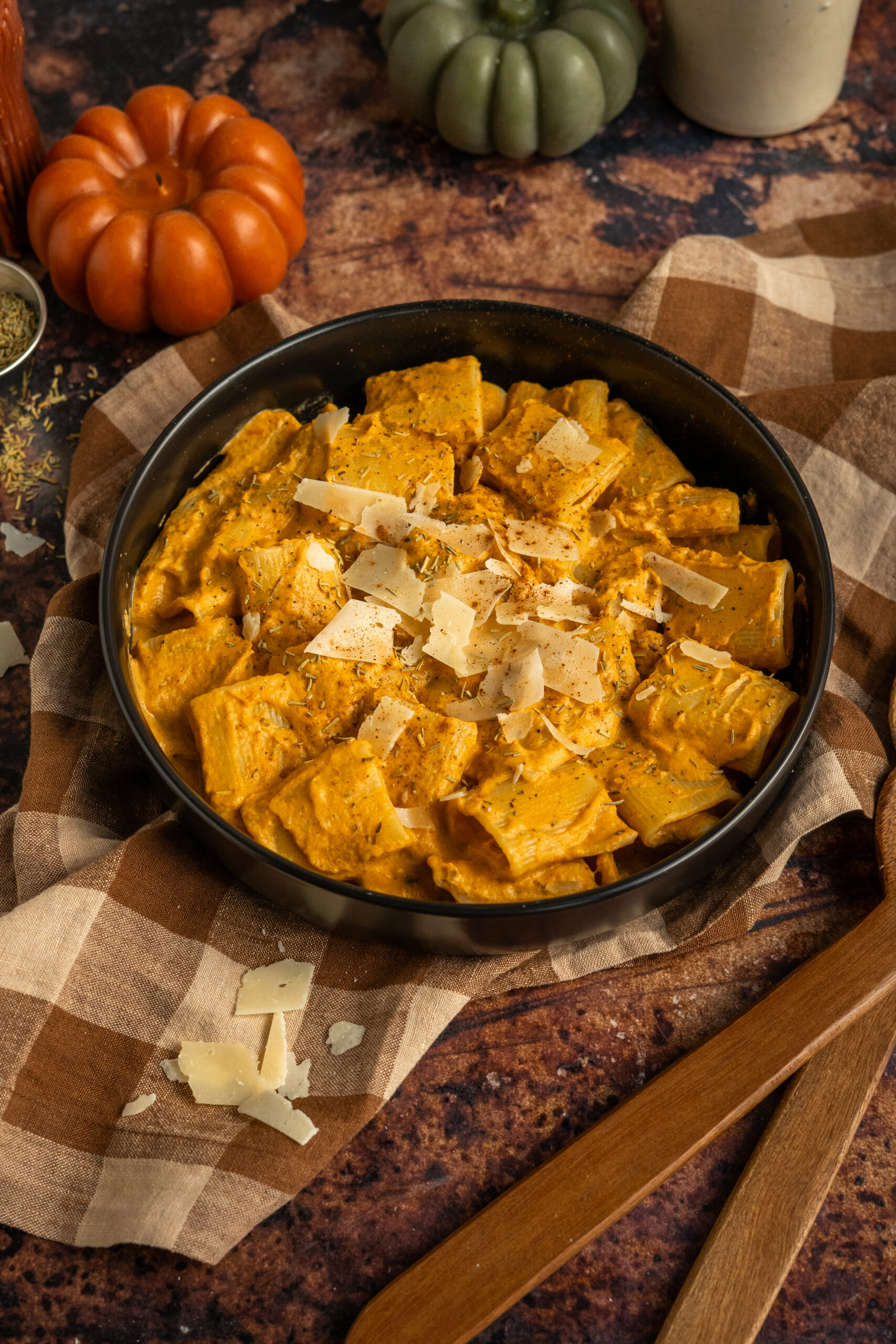 pumpkin pasta in black bowl on a brown backdrop.