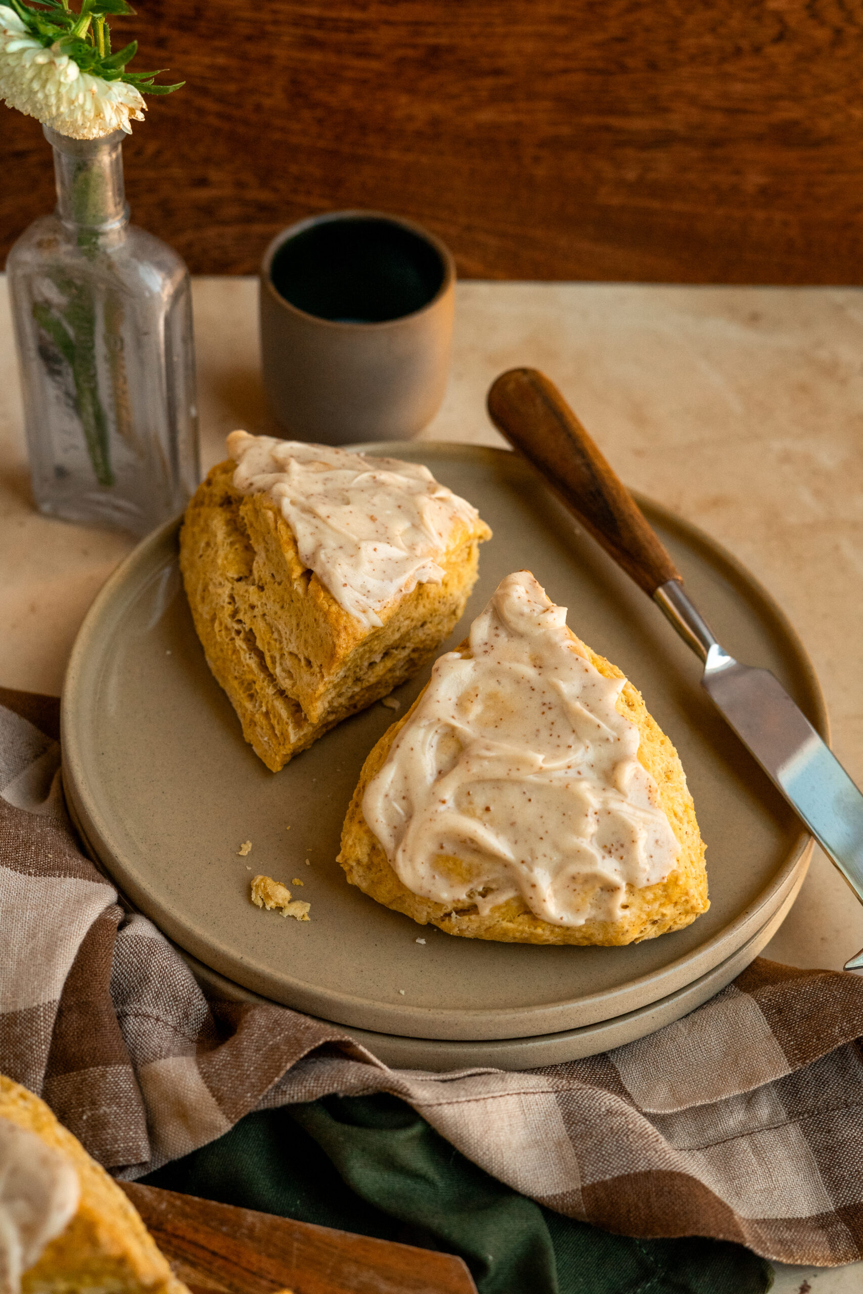 two pumpkin scones on a stack of brown plates.