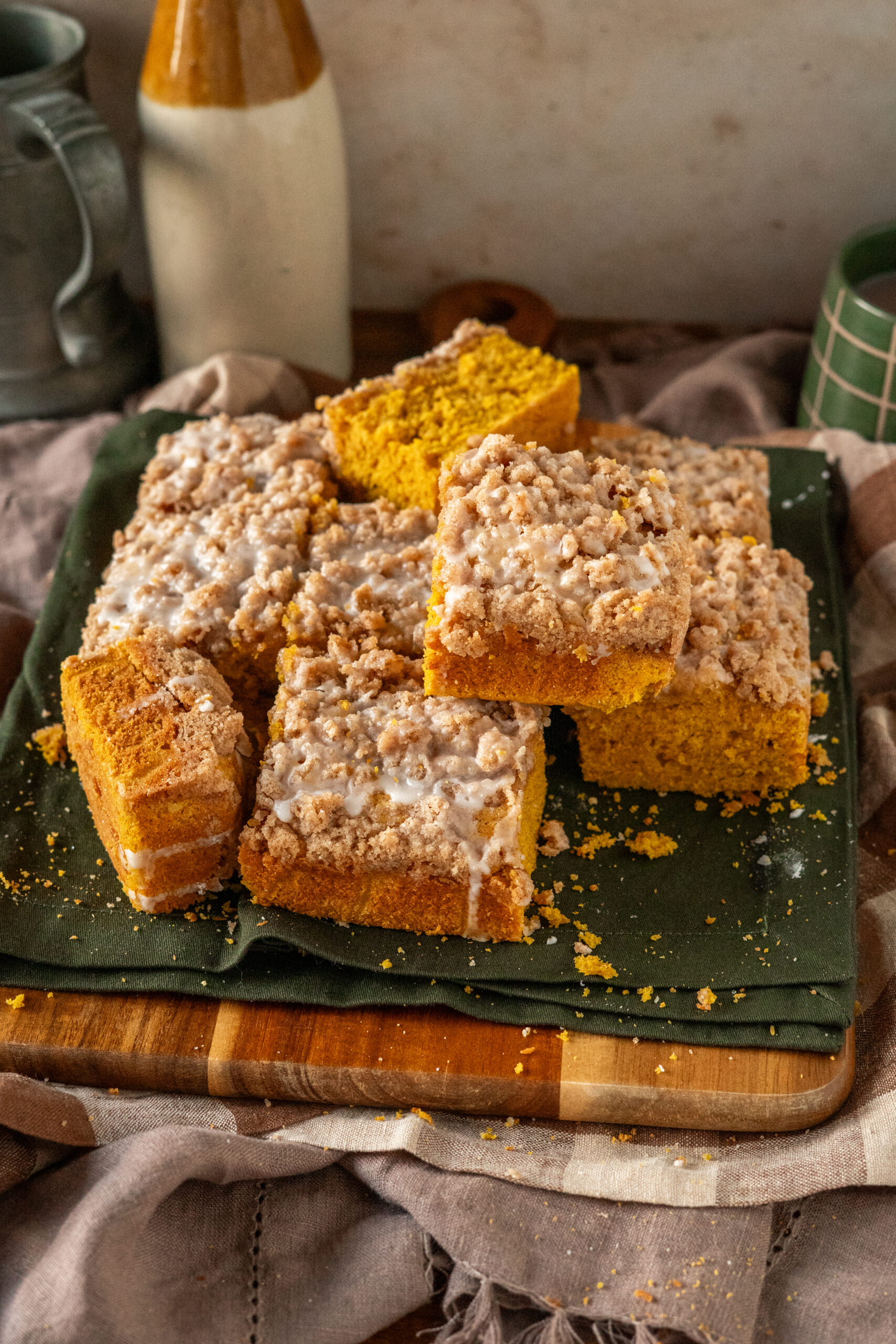 pumpkin coffee cake stacked on green napkin and wooden cutting board.