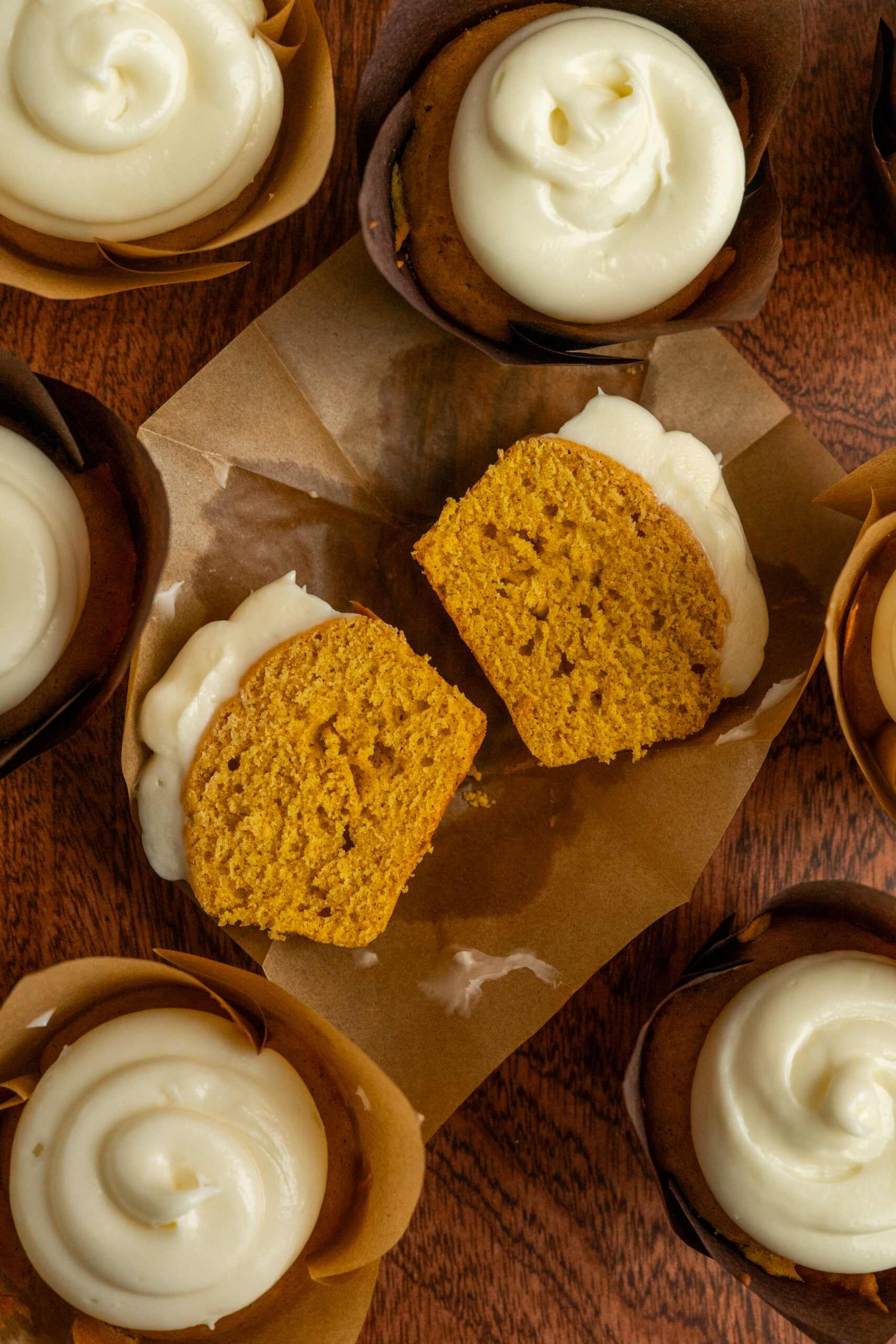 pumpkin spice cupcakes scattered around one cupcake sliced in half.