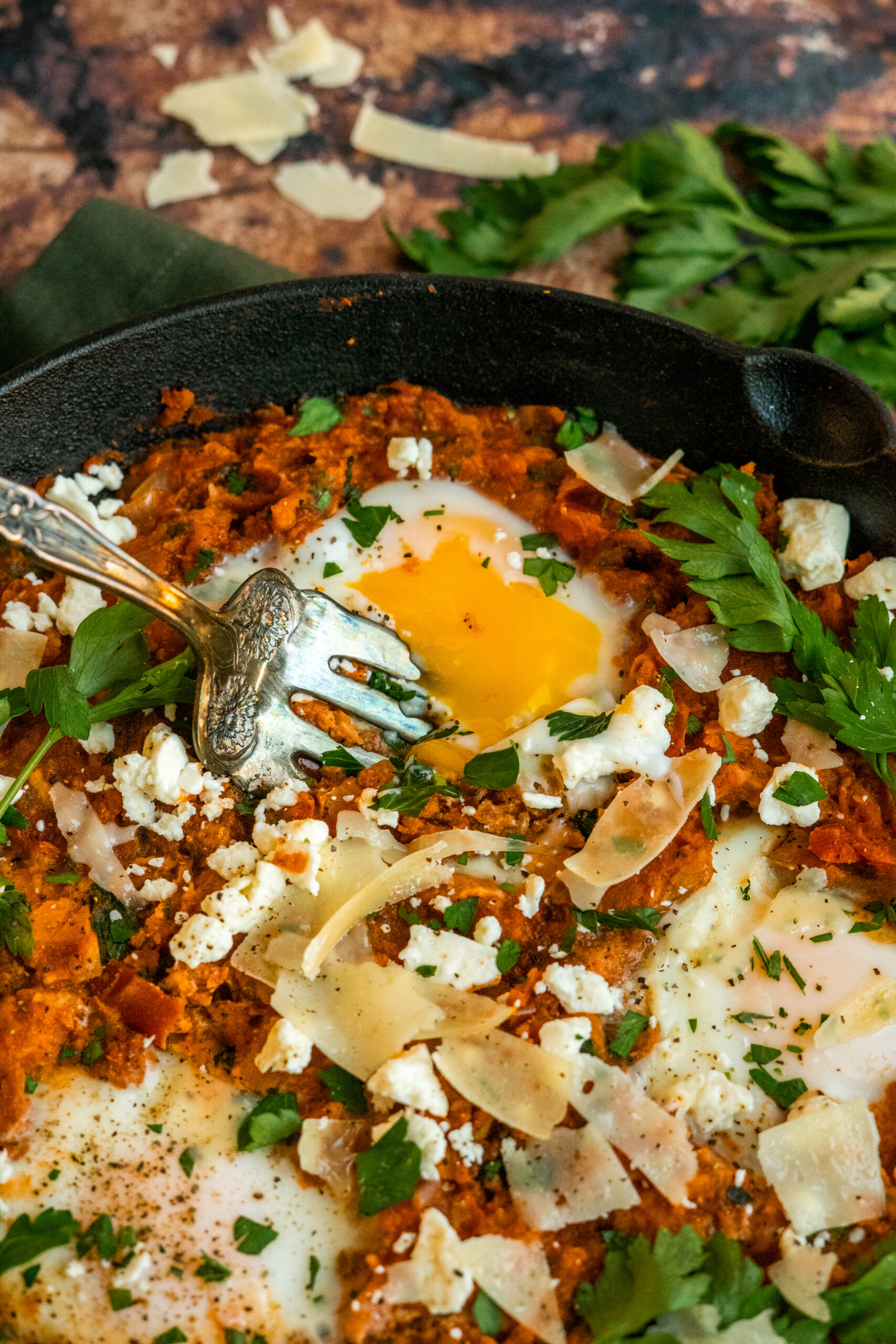 fork poking into a cooked egg in the shakshuka skillet.
