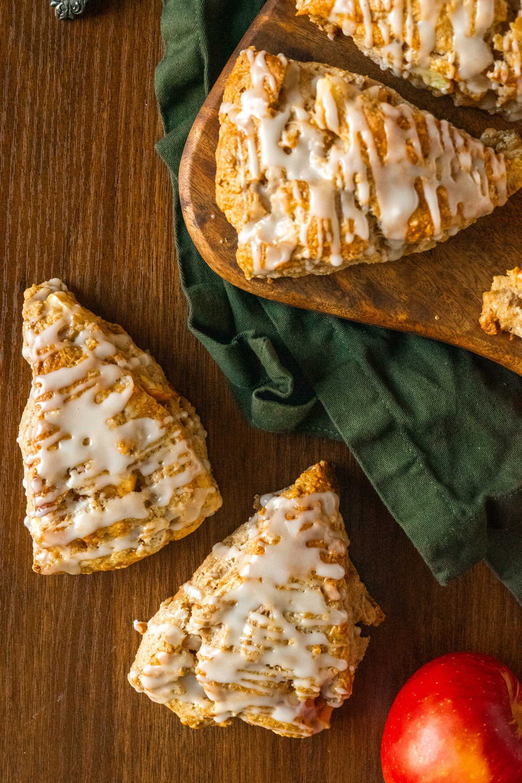 overhead view of apple cider scones on wooden serving board on top of green napkin.