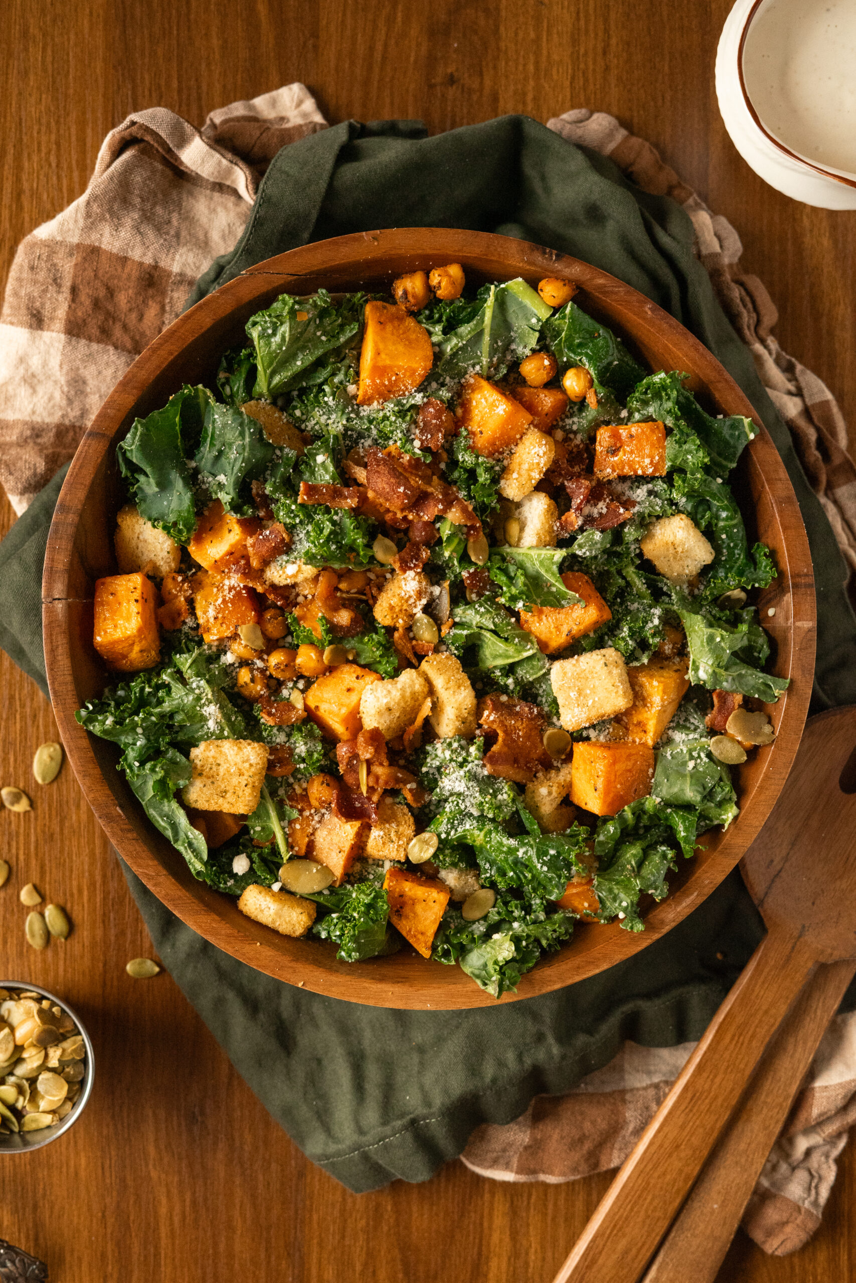 kale caesar salad in wooden bowl on green and brown linens.