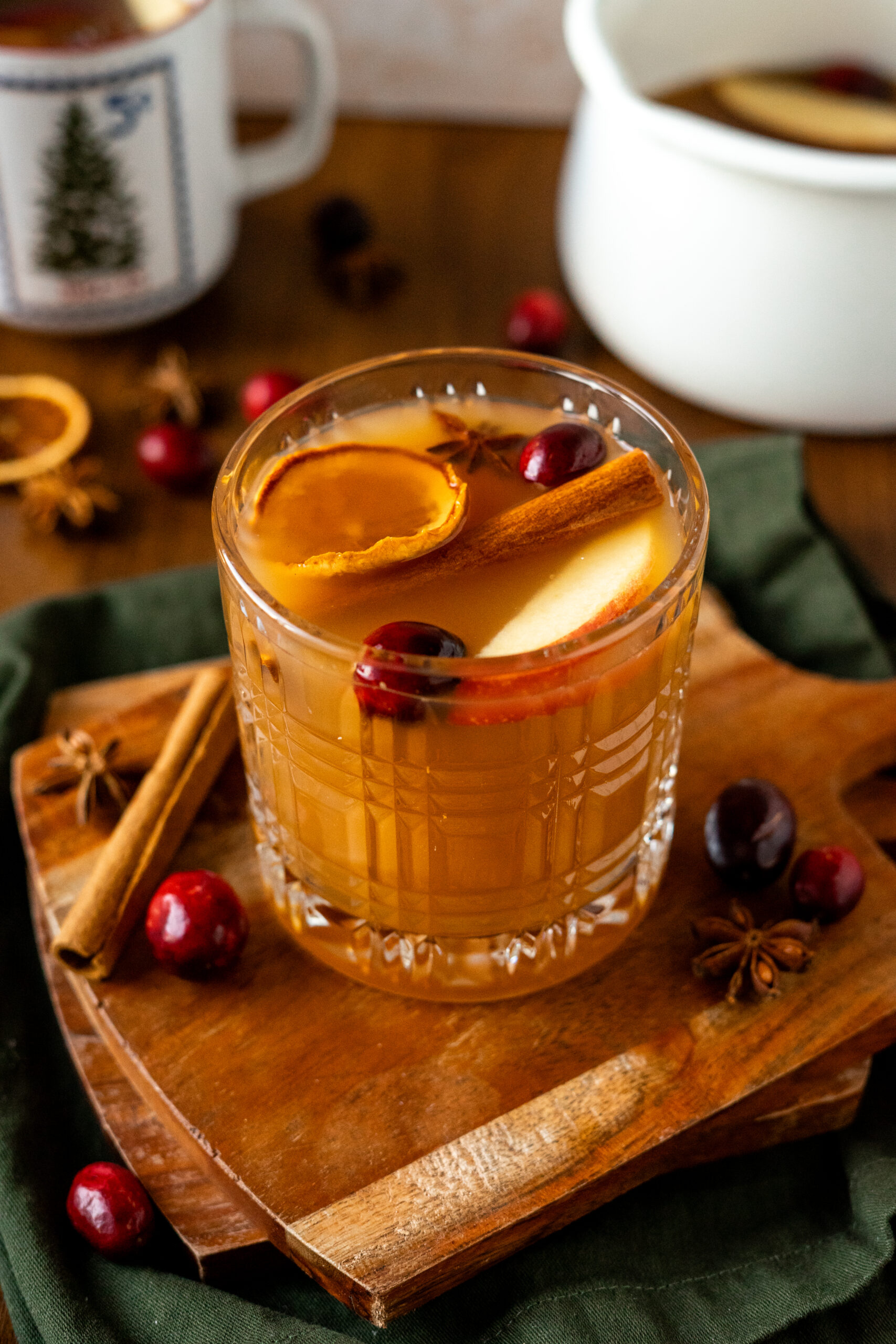 cup of apple cider cocktail on stacked wooden coasters.