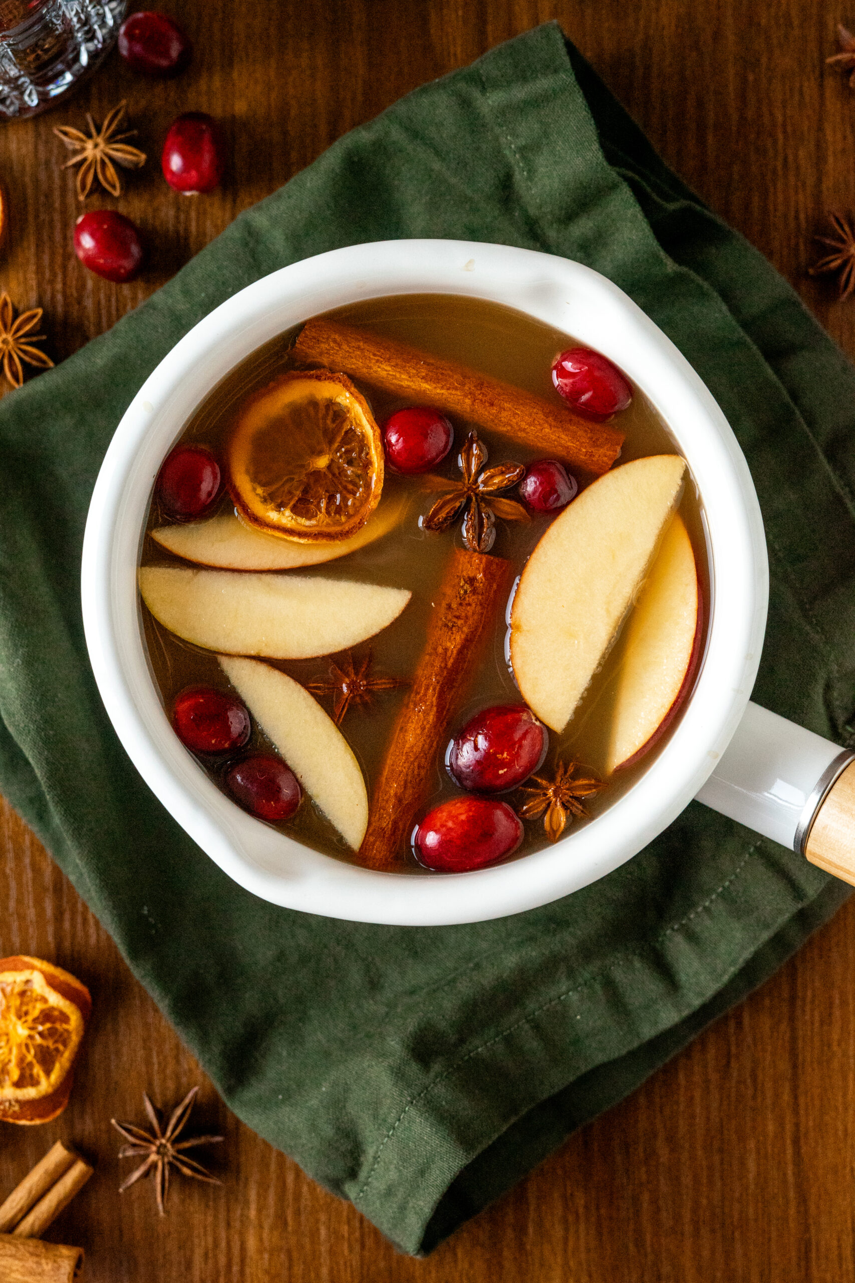 apple cider simmer pot on a green napkin and wooden surface.