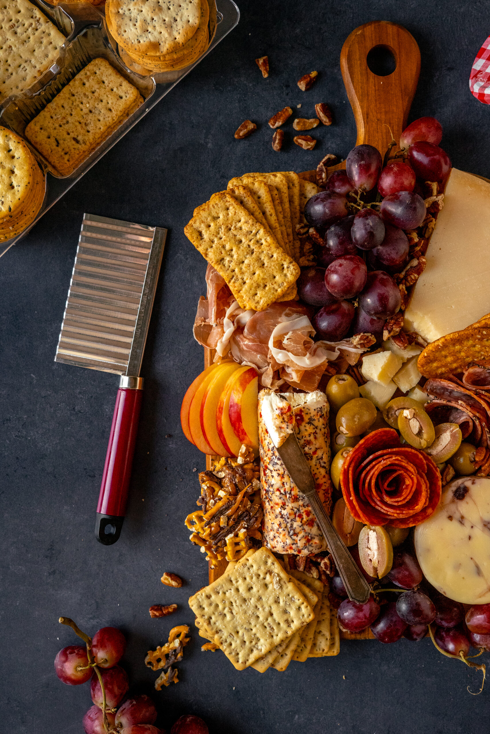 autumn charcuterie board on dark background with fluted cheese knife to the side.